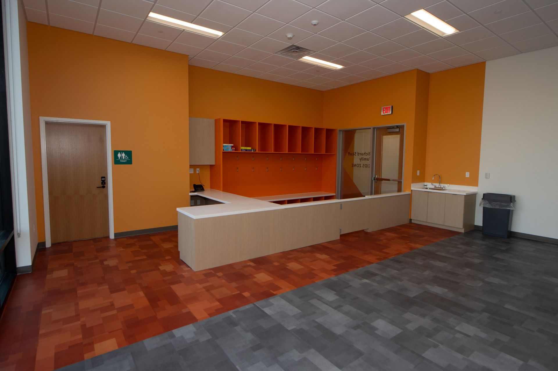 An empty room with orange walls and a handicap sign on the door