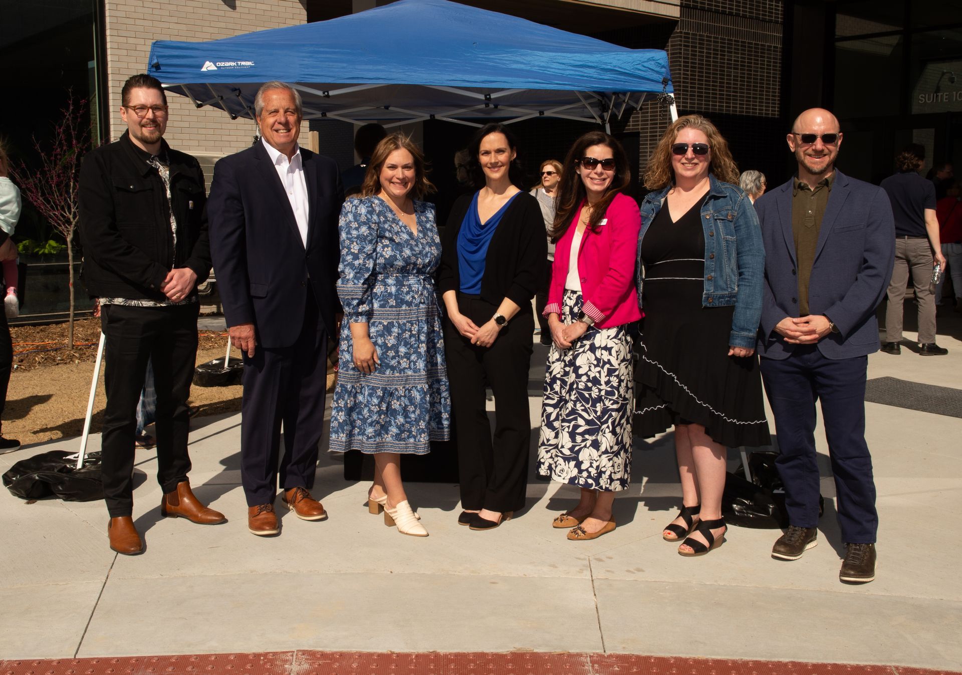 A group of people standing in front of a blue tent.
