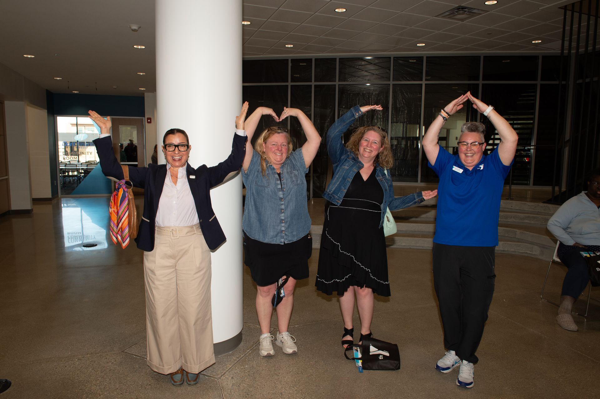 Four women are posing for a picture with their hands in the air