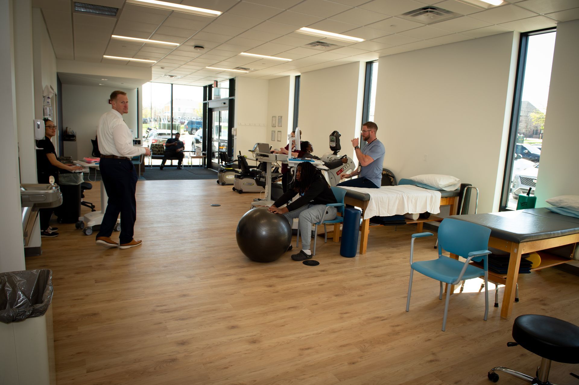 A woman is sitting on a ball in a physical therapy room.