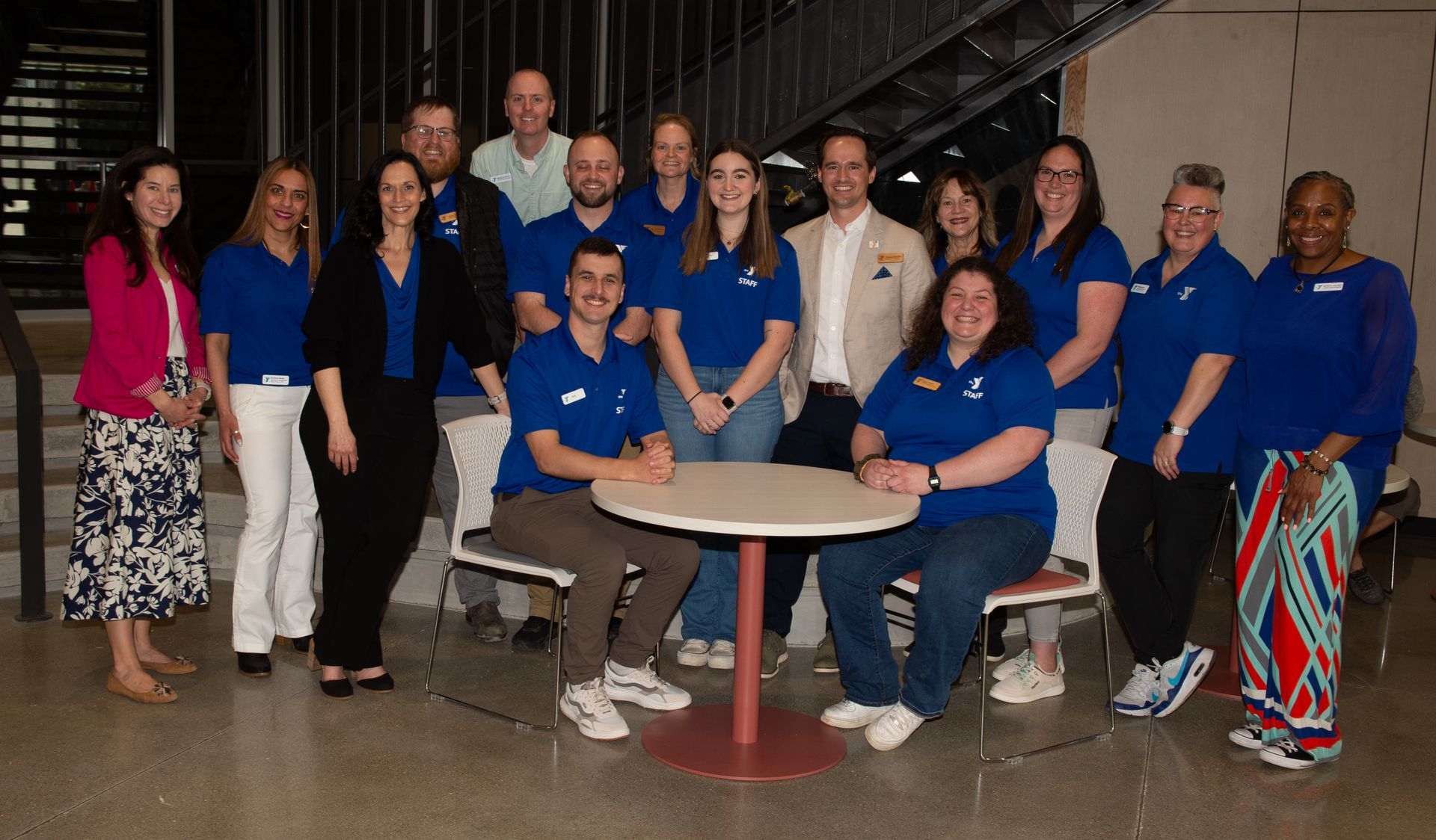 A group of people in blue shirts are posing for a picture