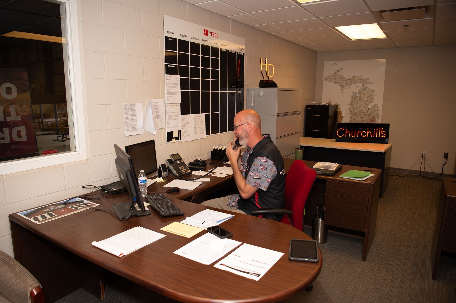 A man is sitting at a desk talking on a cell phone.