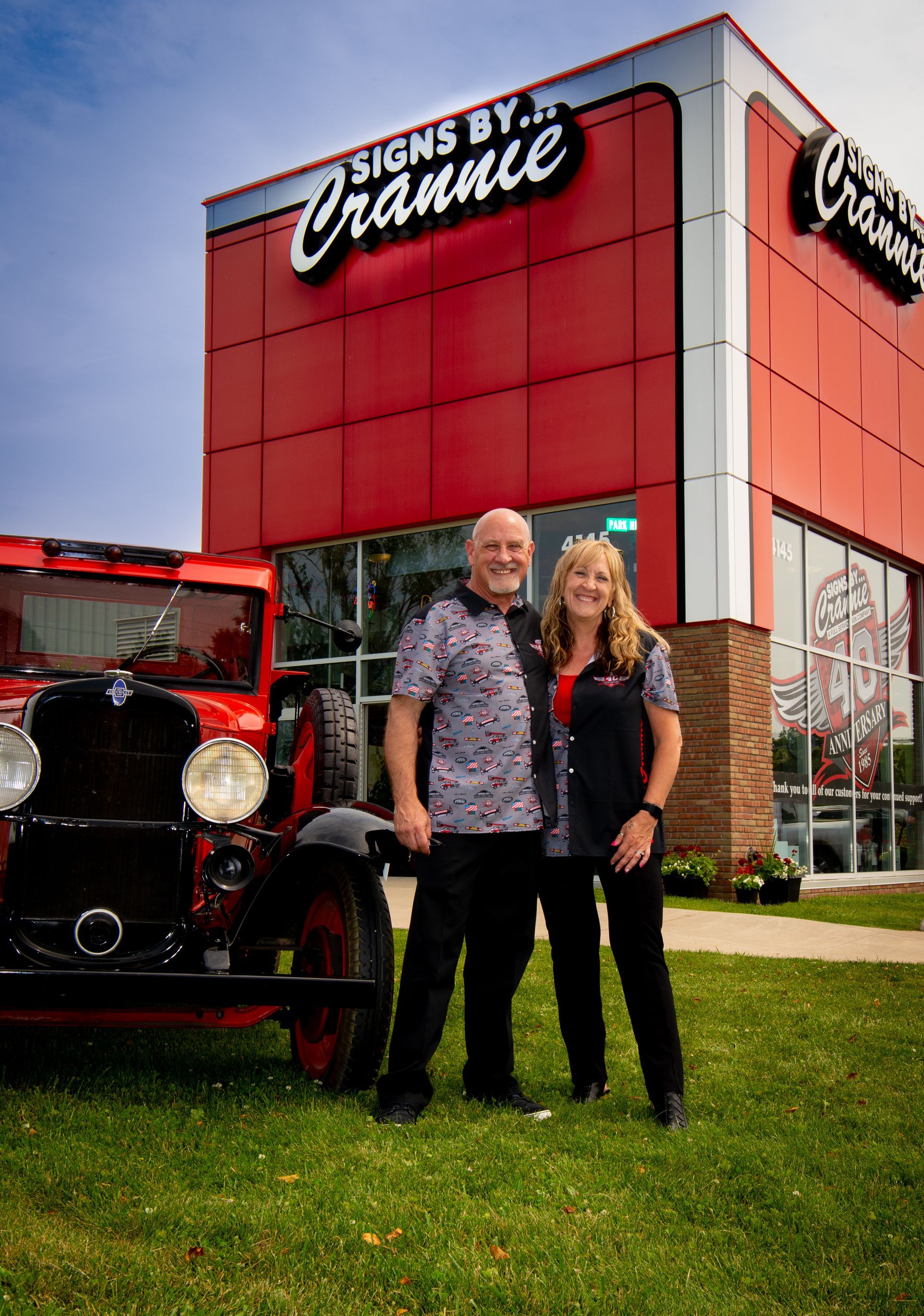 A man and a woman are standing in front of a red truck.