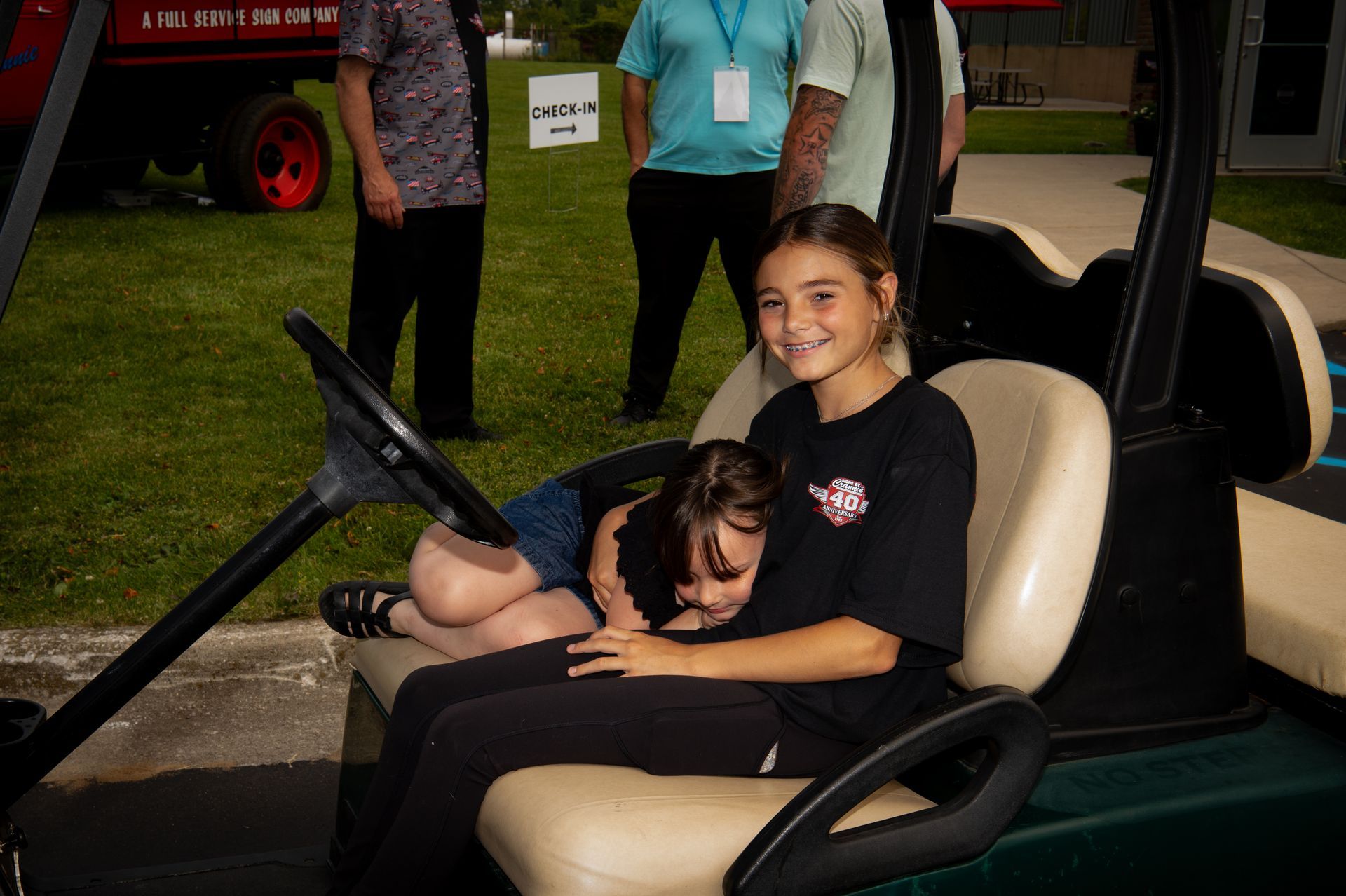 Two young girls are sitting in a golf cart.