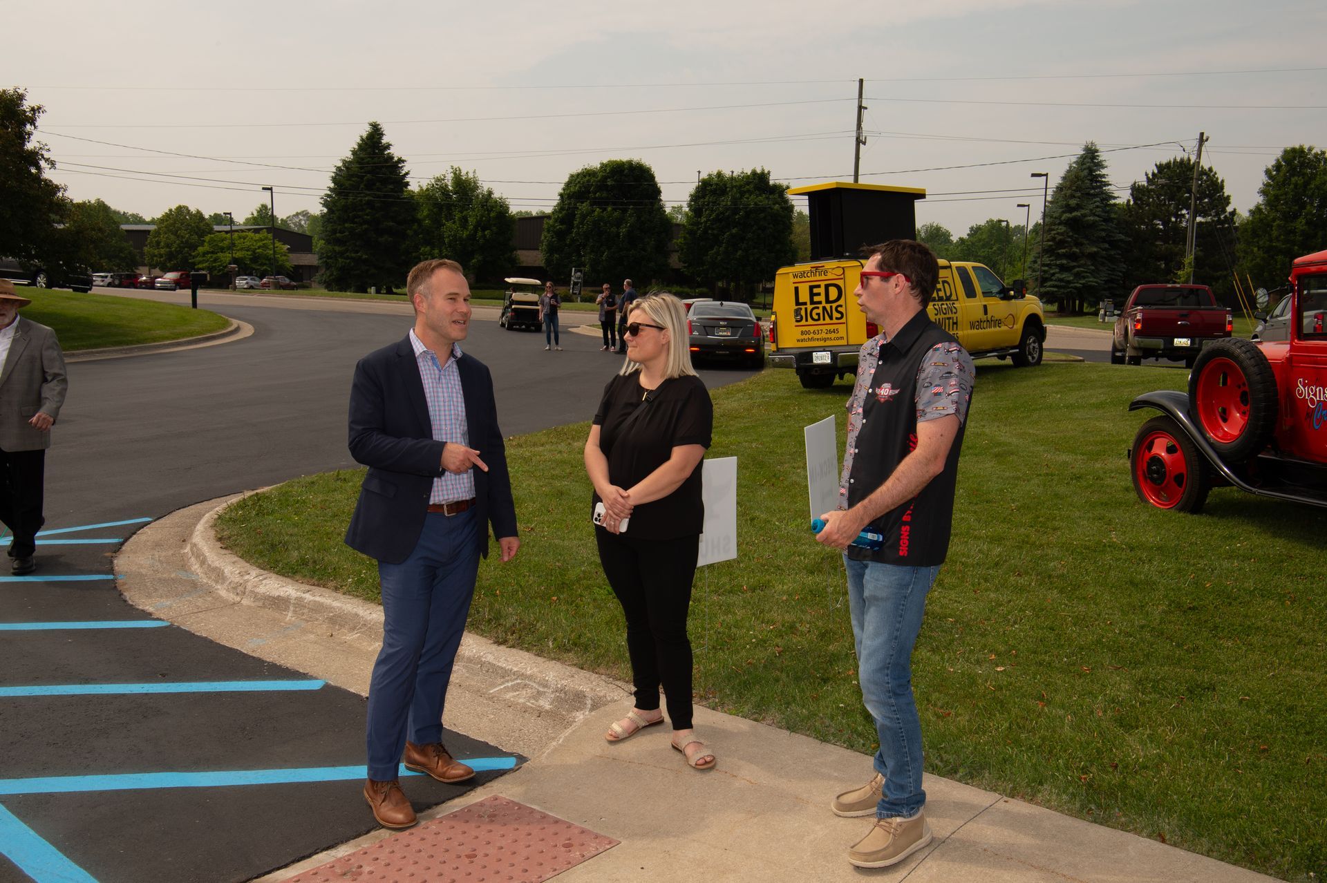 A group of people are standing in a parking lot talking to each other.