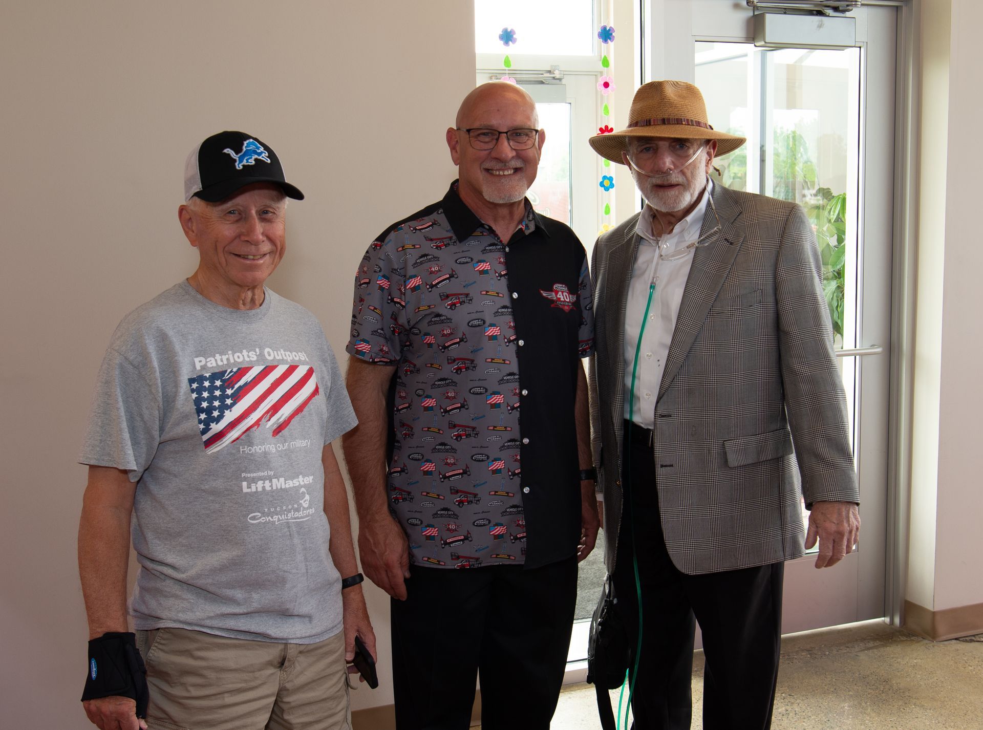 Three men are posing for a picture in a hallway.