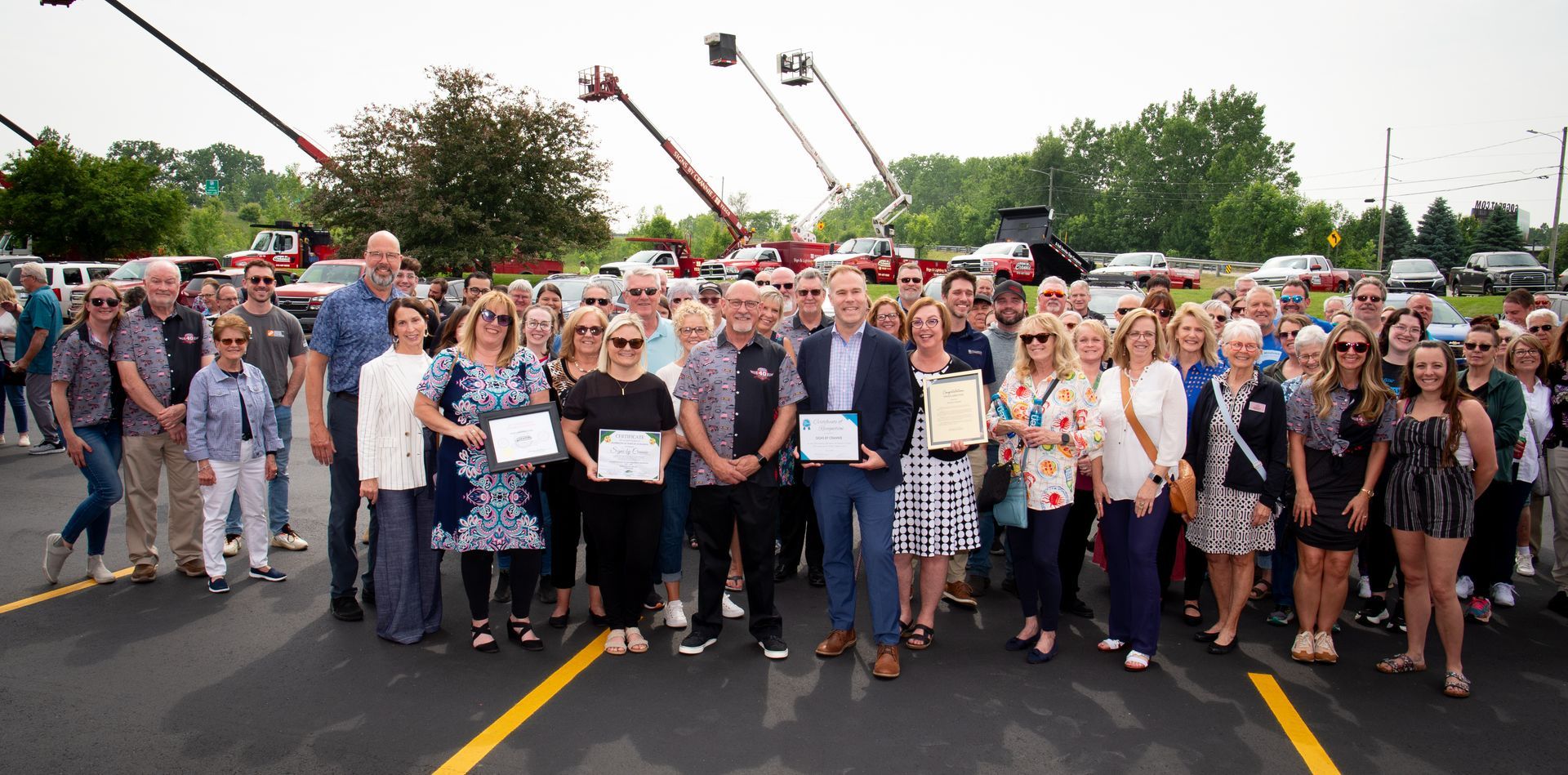 A large group of people are posing for a picture in a parking lot.