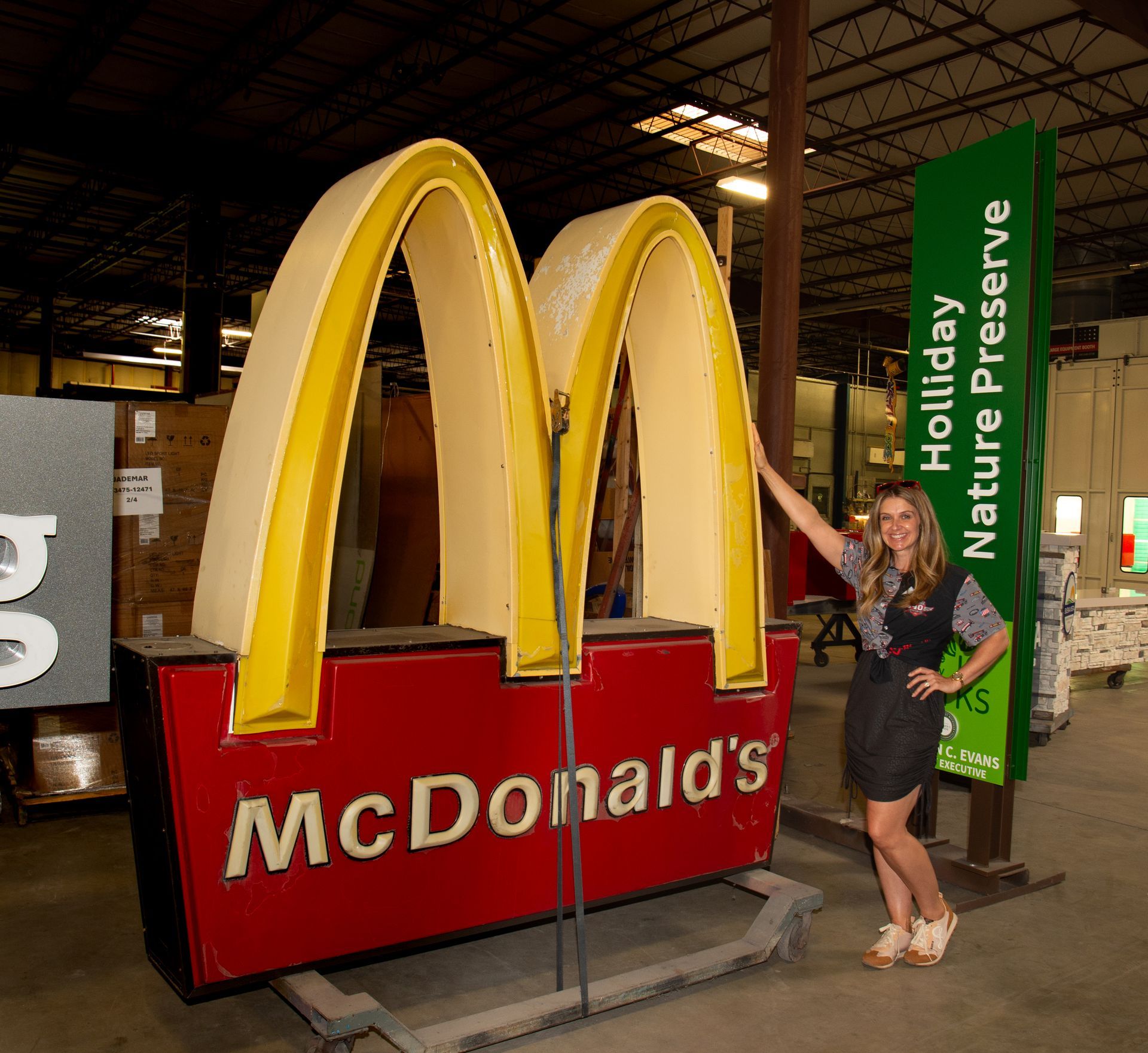 A woman stands in front of a large mcdonald 's sign