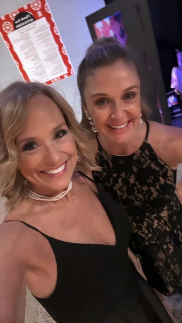 Two women are posing for a picture together and smiling for the camera.