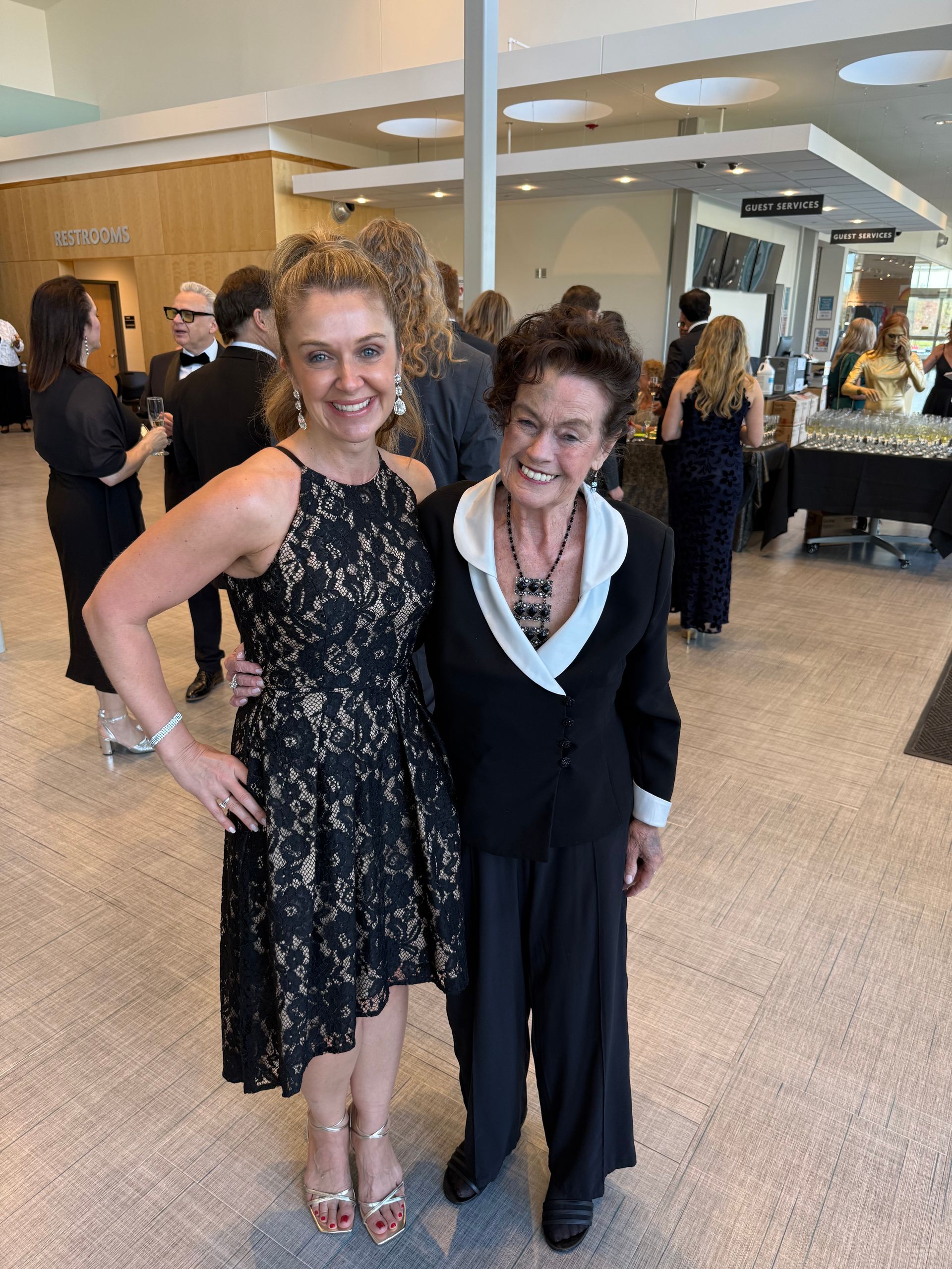 Two women are posing for a picture together in a lobby.