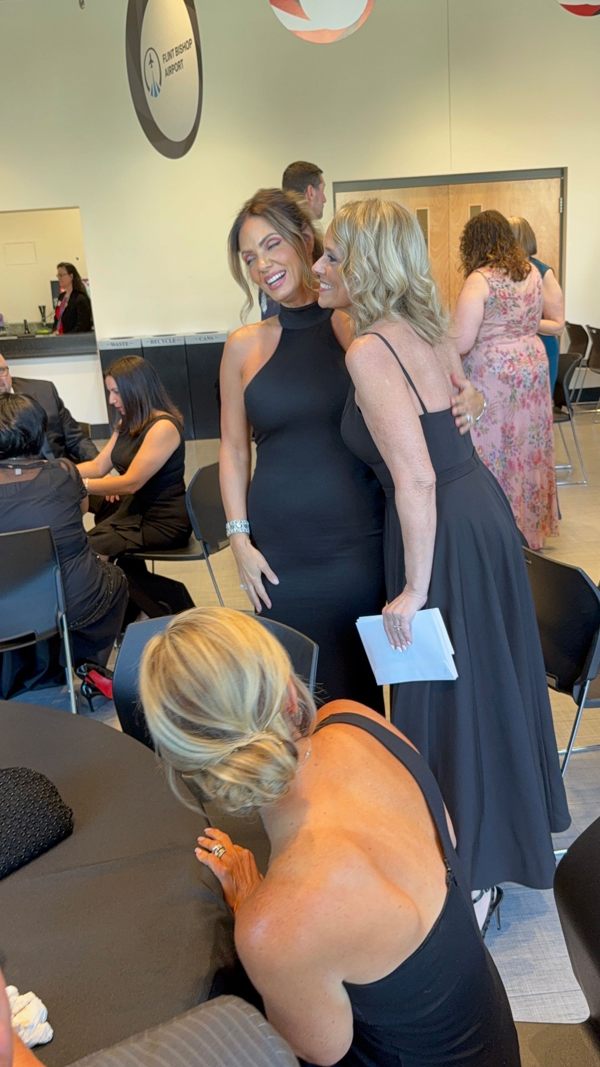A group of women in black dresses are standing next to each other in a room.