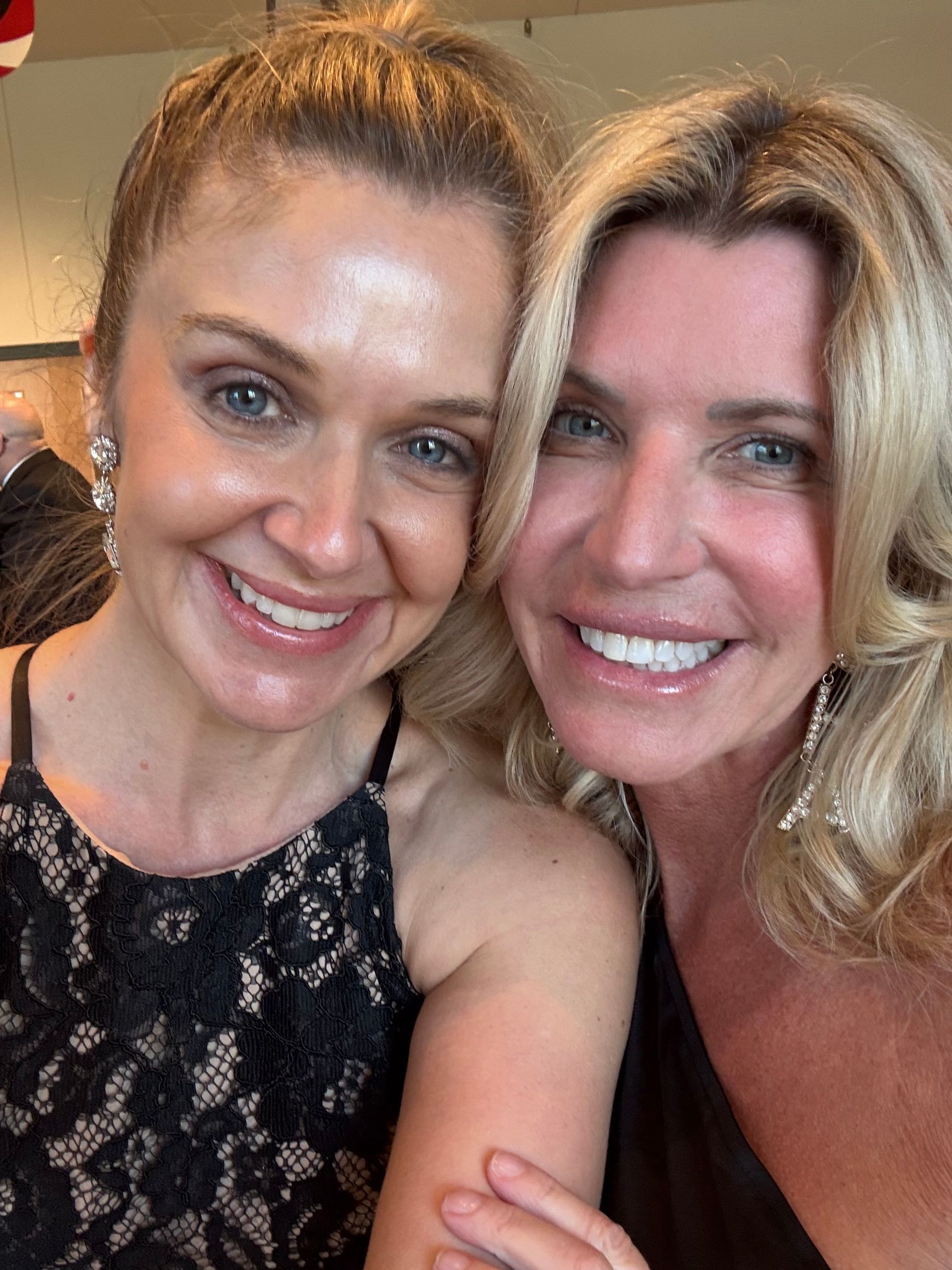 Two women are posing for a picture together and smiling for the camera.