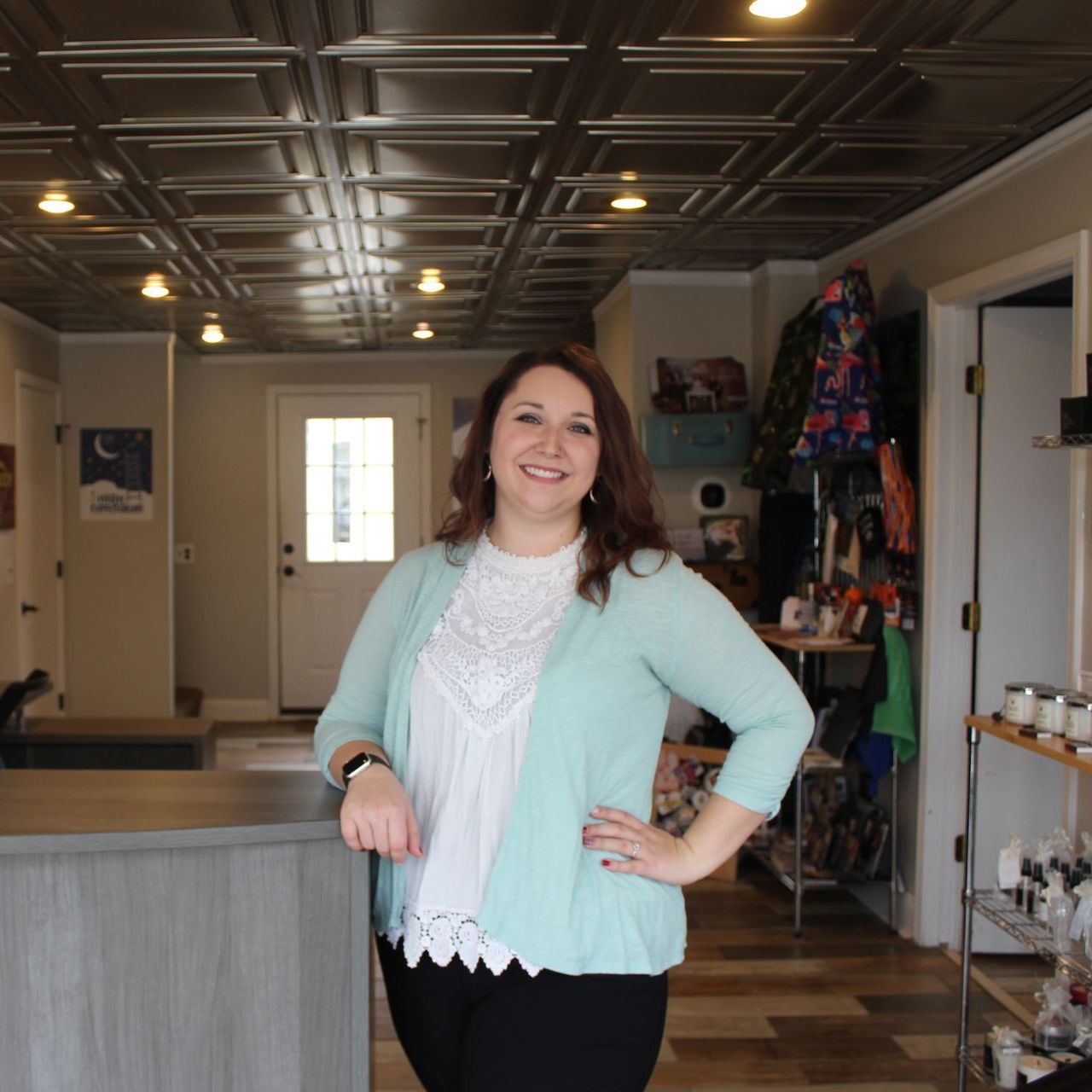 A woman in a light blue cardigan is standing in front of a counter
