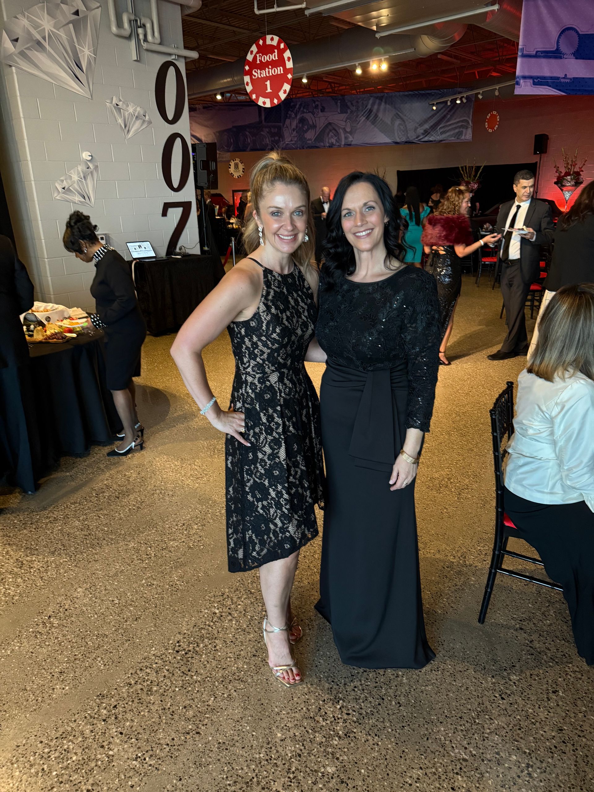 Two women in black dresses are posing for a picture in a room.