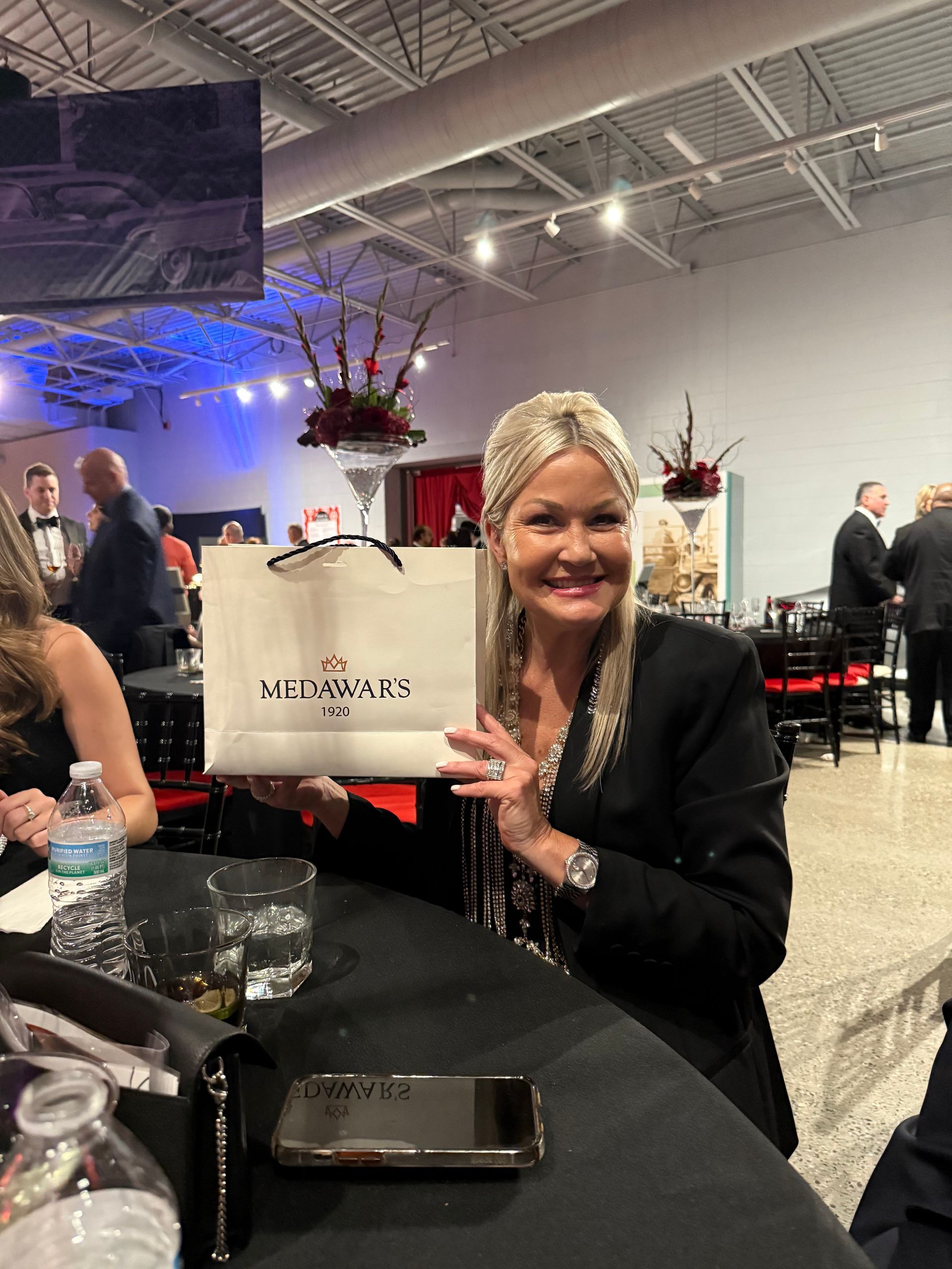 A woman is sitting at a table holding a white bag.