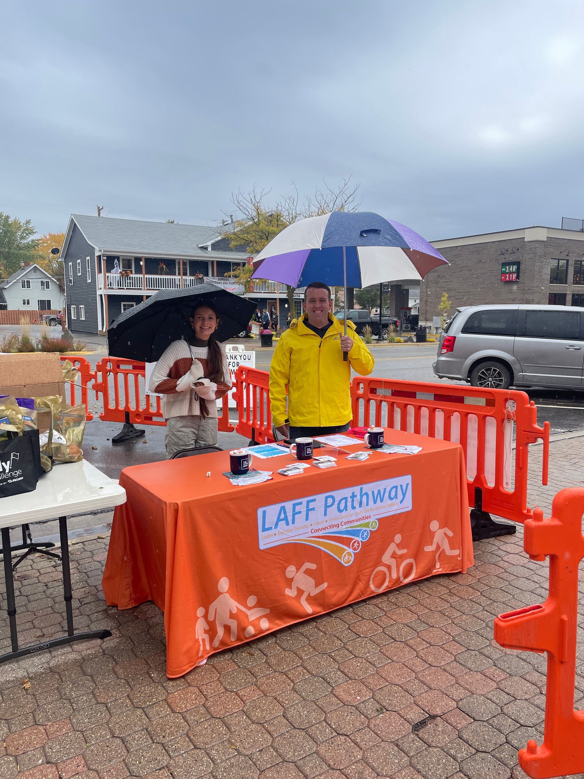 A man and a woman standing behind a table with umbrellas.