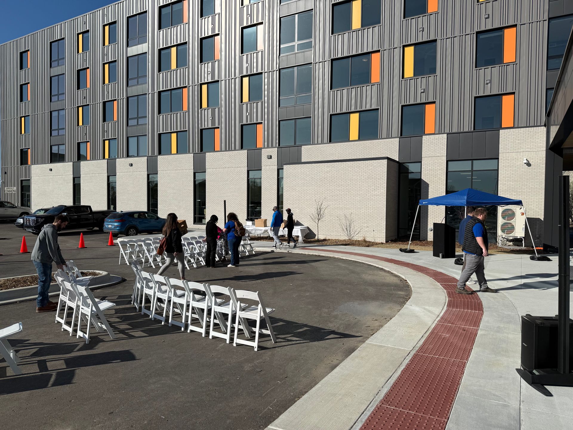A row of white chairs are lined up in front of a large building