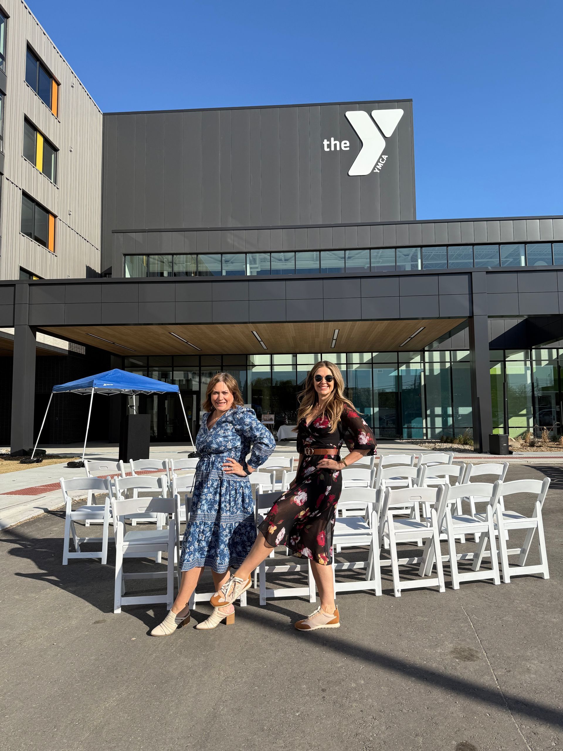 Two women are standing in front of a building with a y on it.