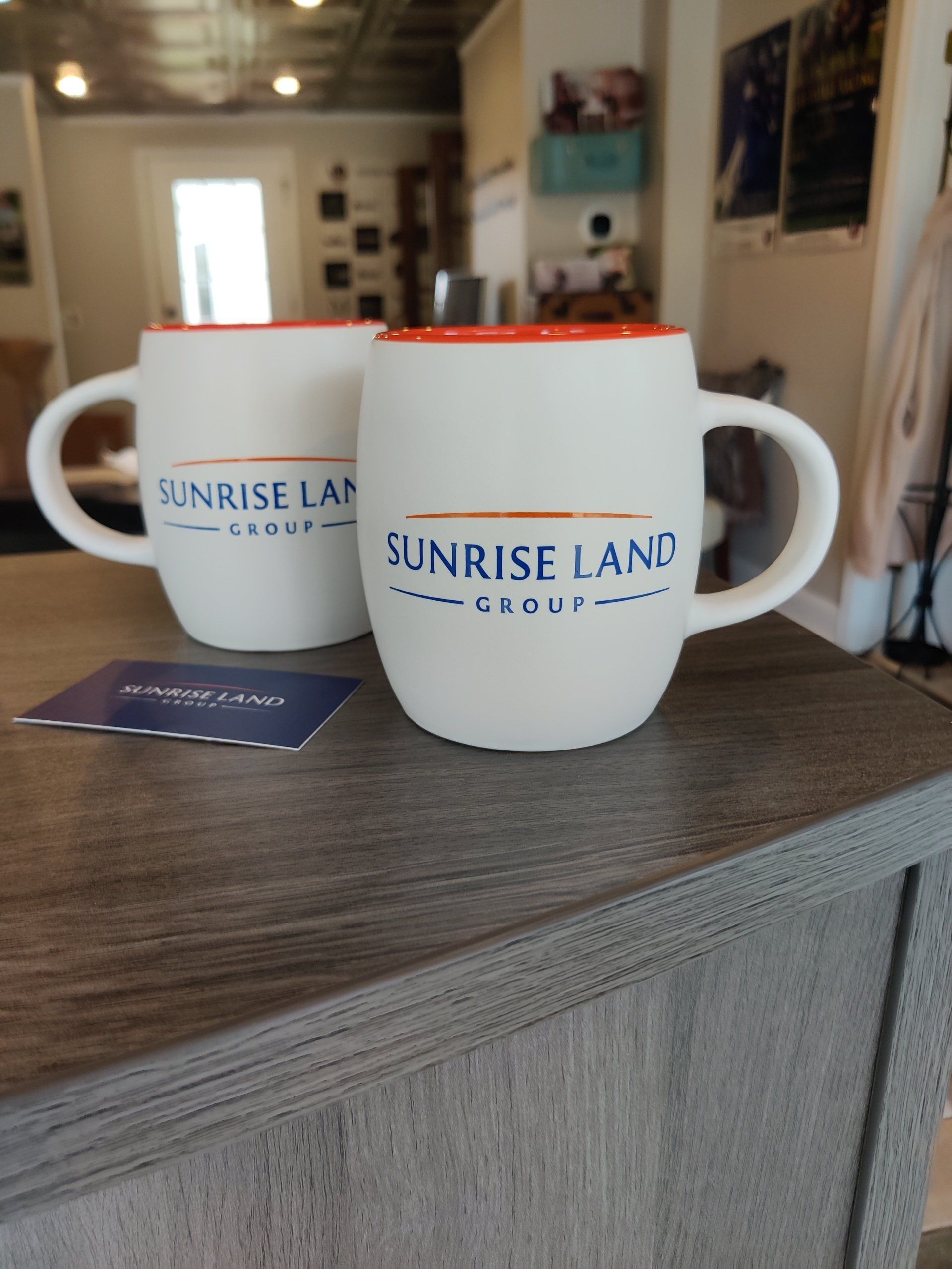Two sunrise land coffee mugs are sitting on a counter