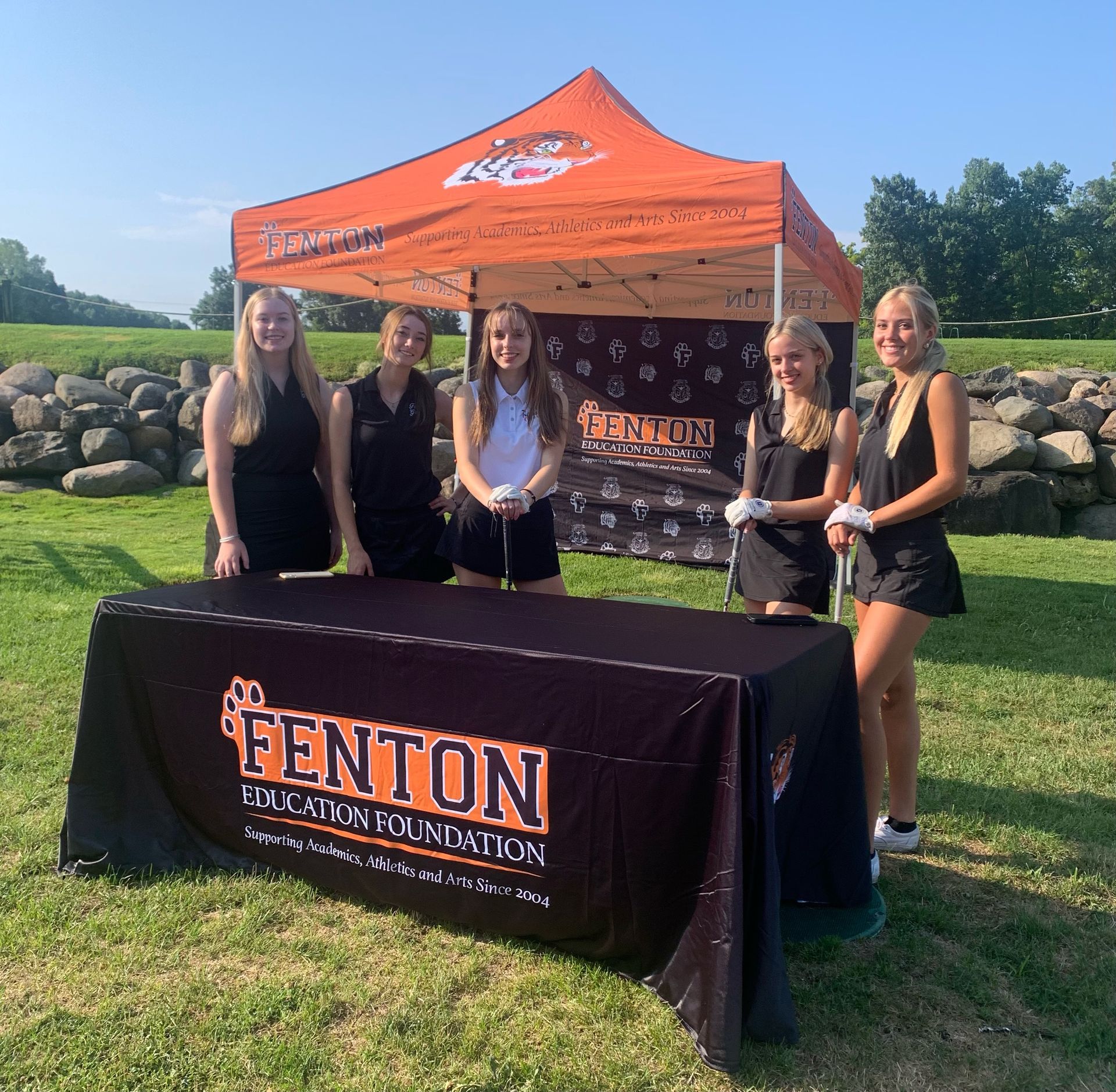 A group of women standing around a table that says fenton