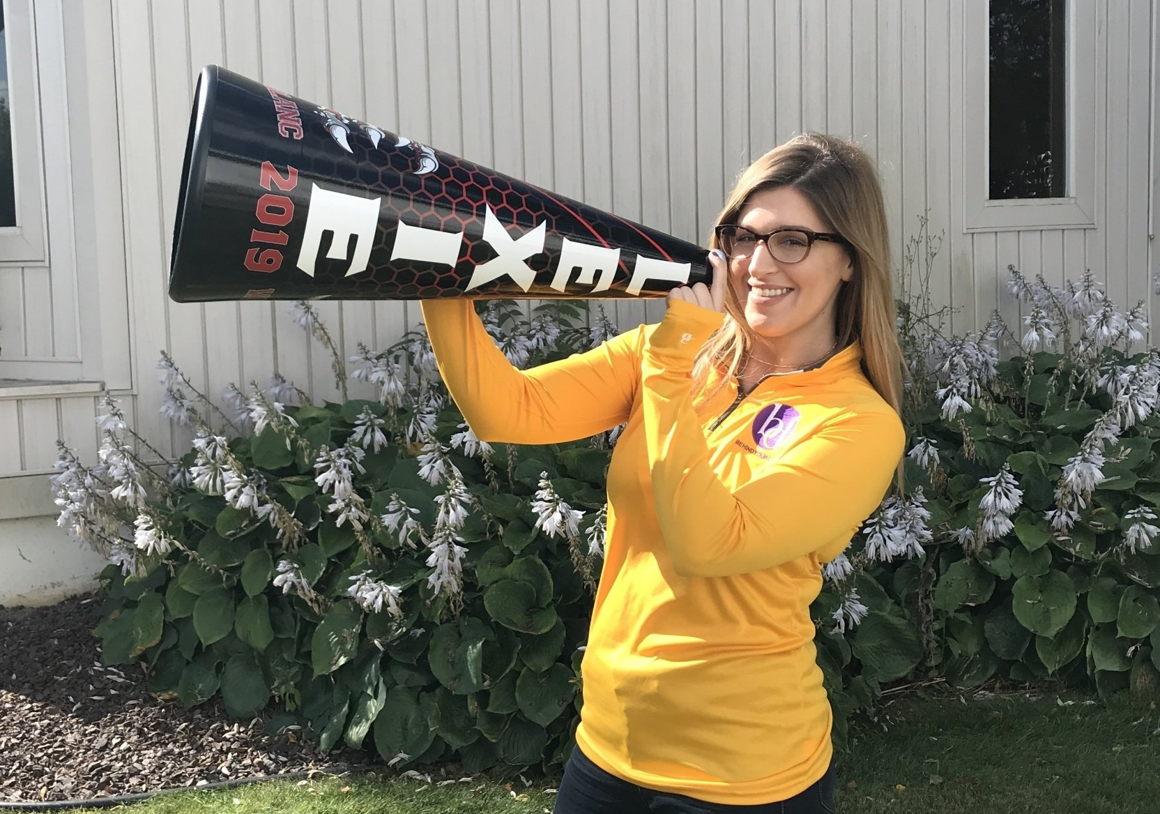 A woman in a yellow shirt is holding a megaphone.