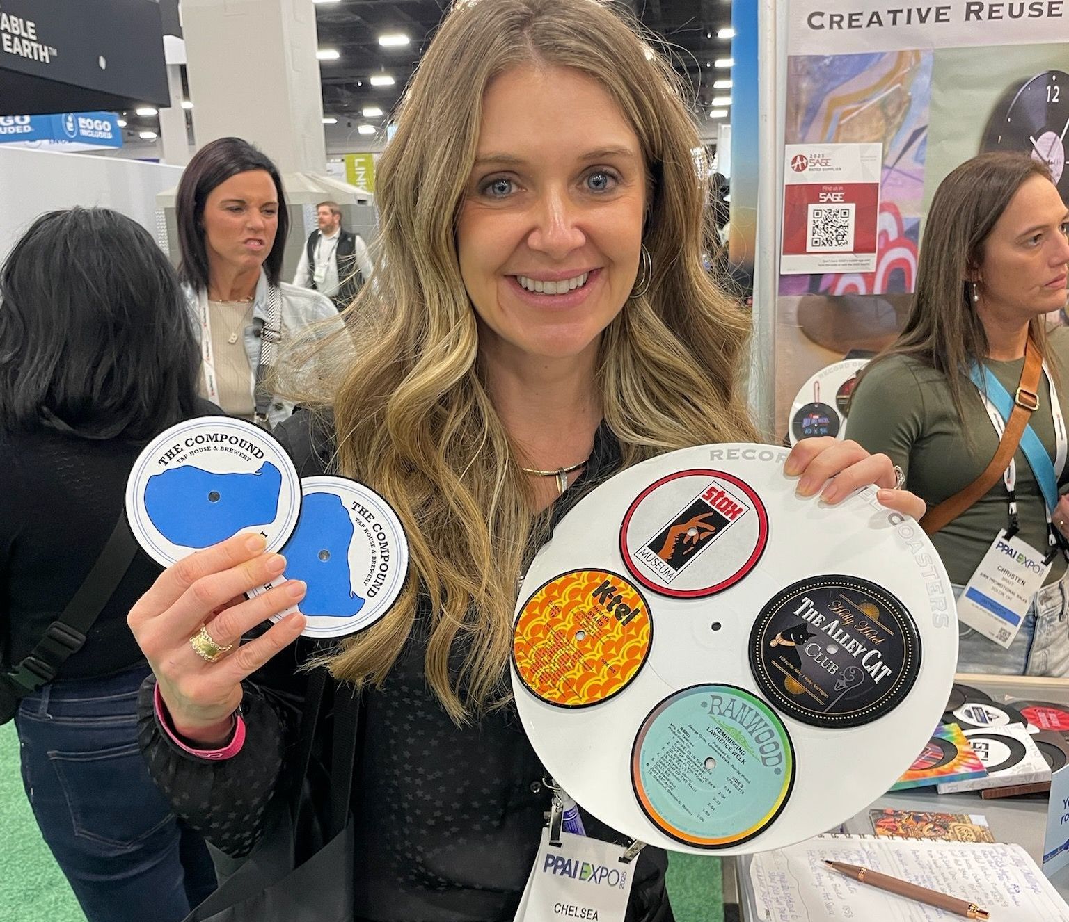 A woman is holding a plate with stickers on it at a convention.