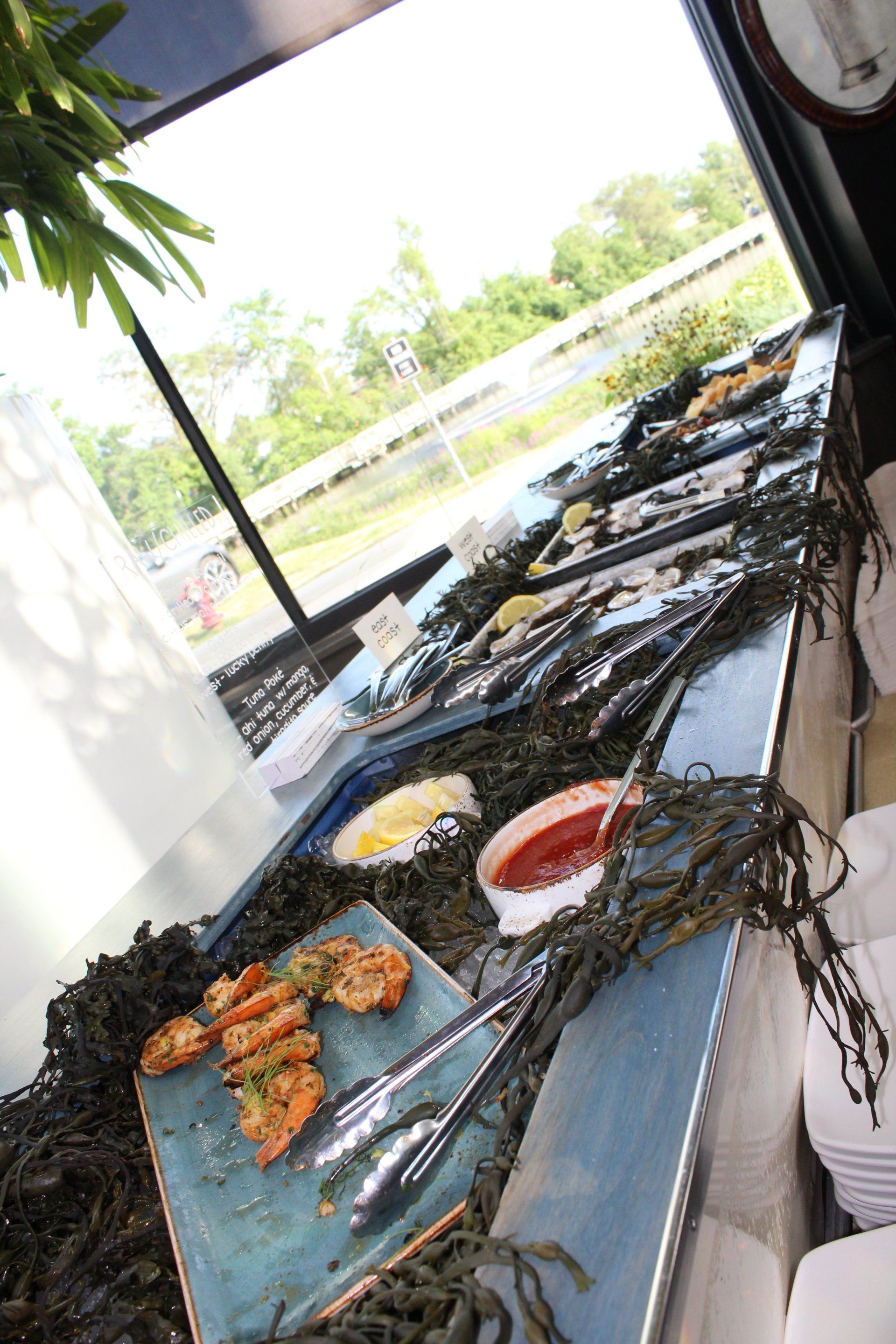 A buffet table with plates of food and tongs on it.