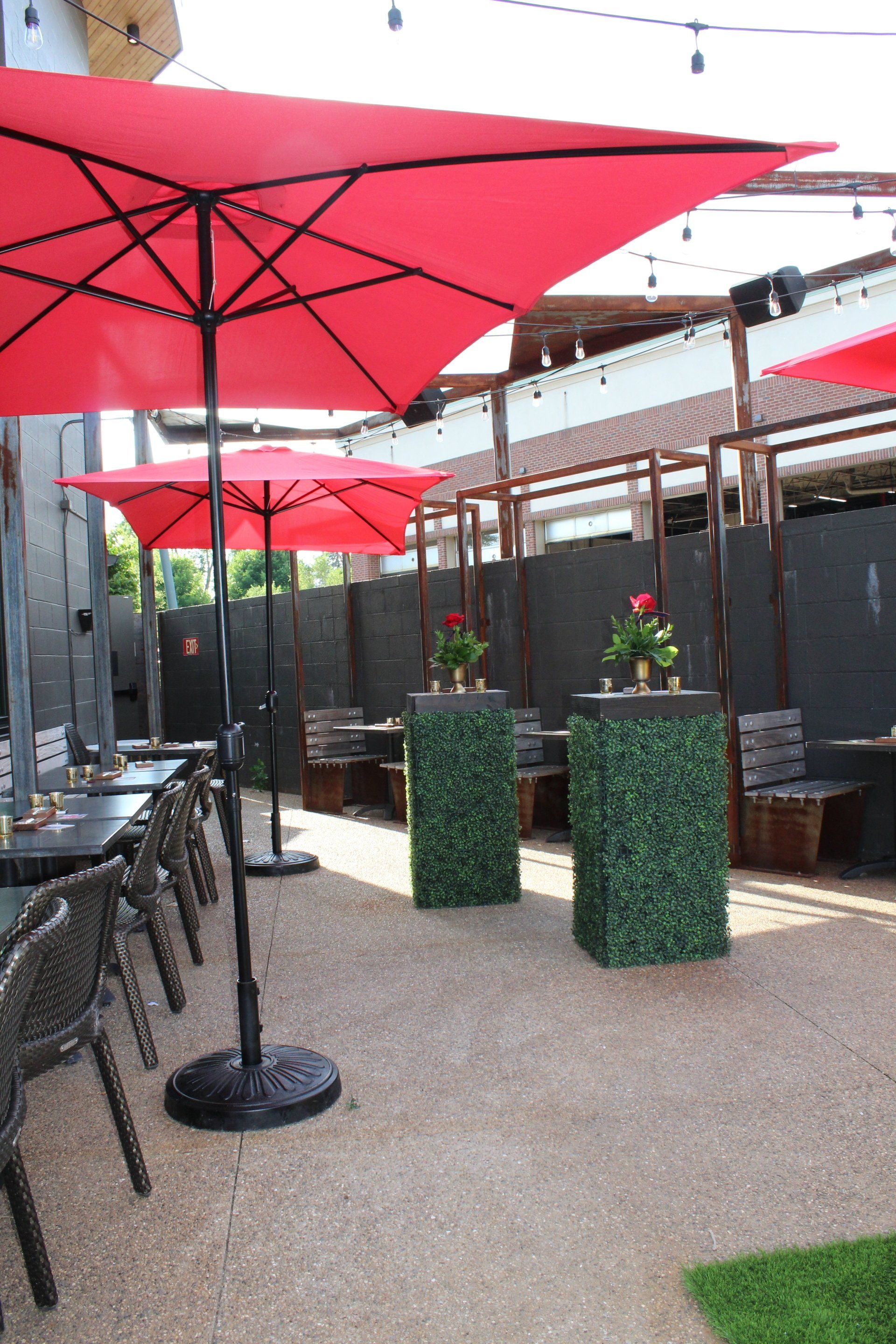 A patio with red umbrellas and tables and chairs