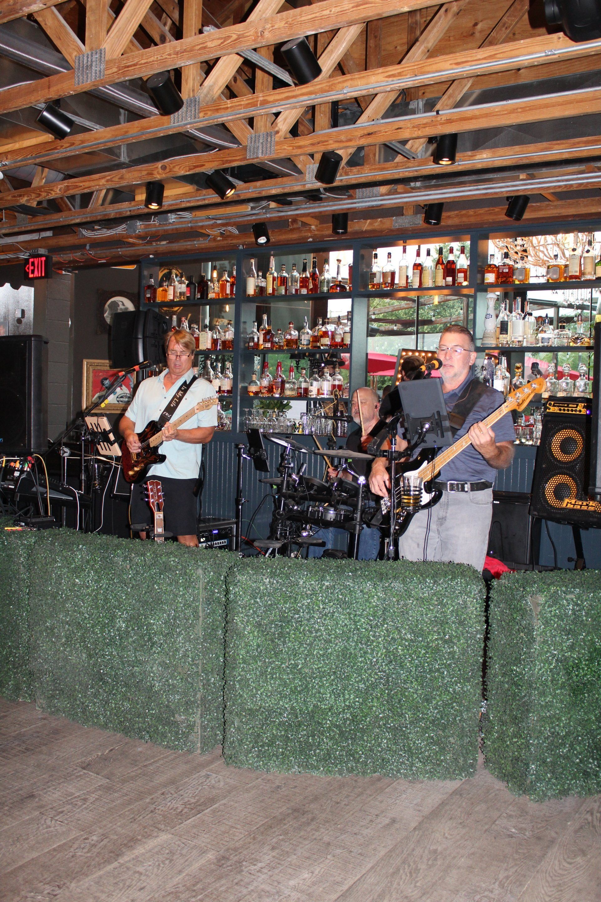 A man is playing a guitar in a band in a bar.