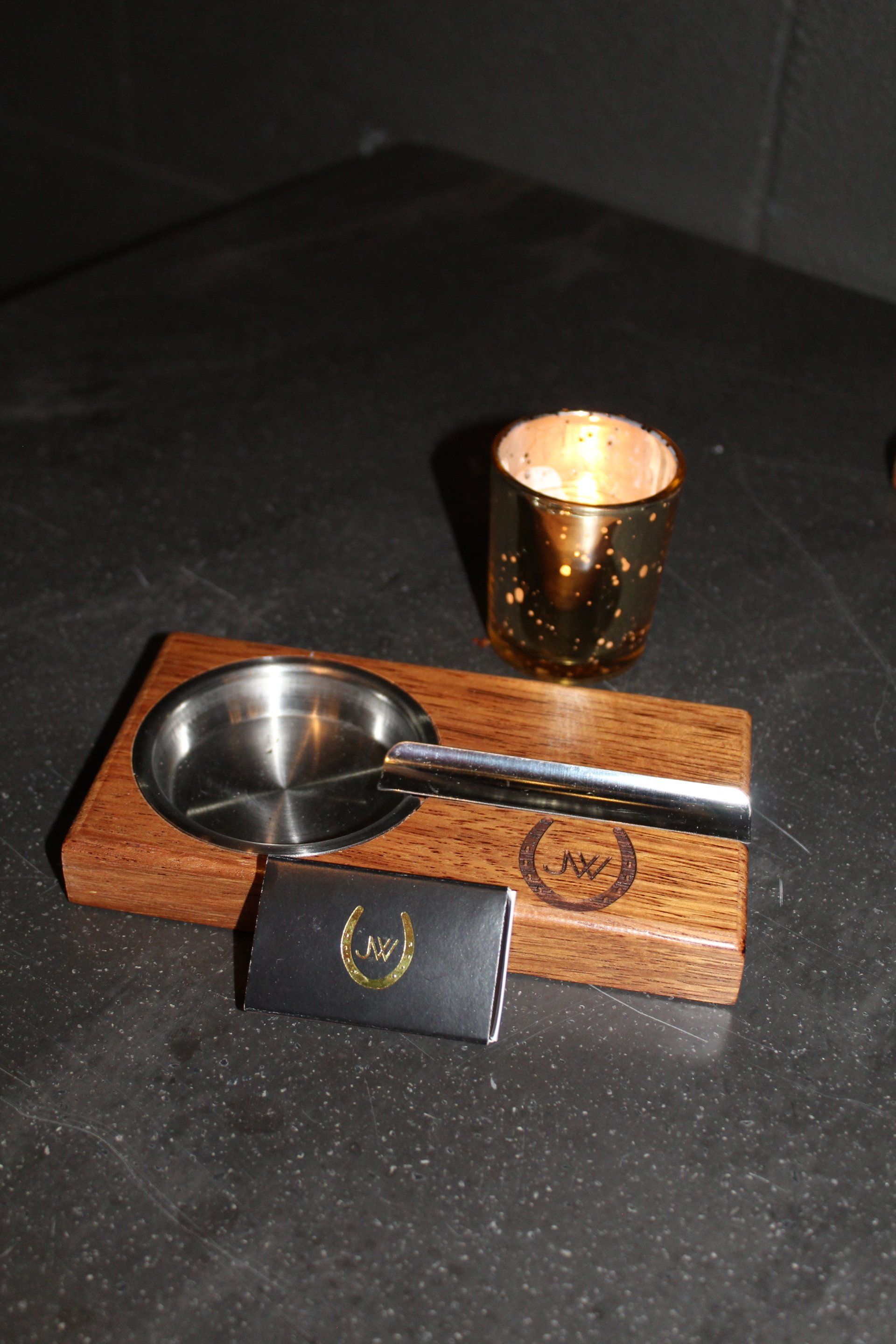 A wooden ashtray and a candle on a table