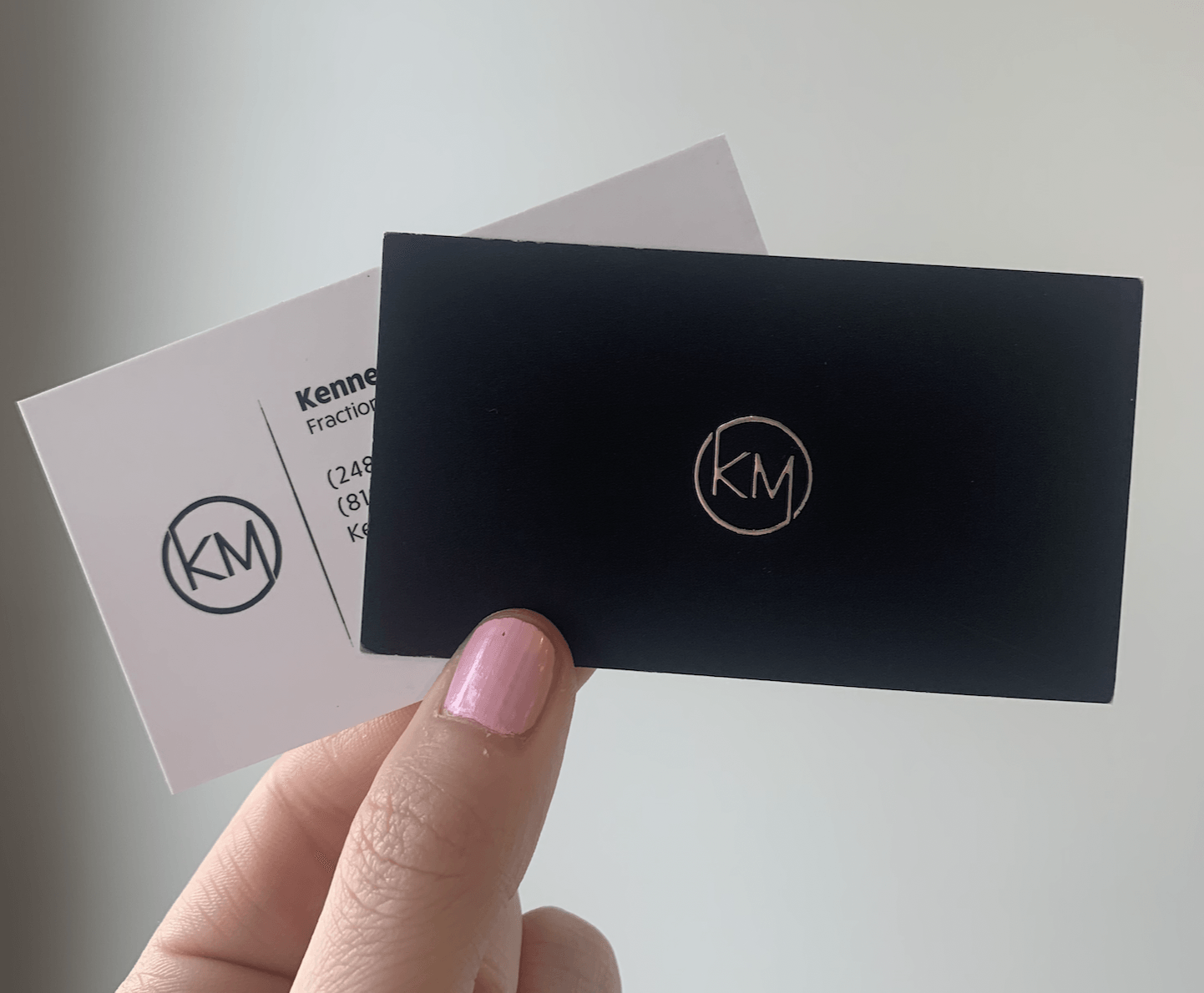 A person is holding a business card with km on it