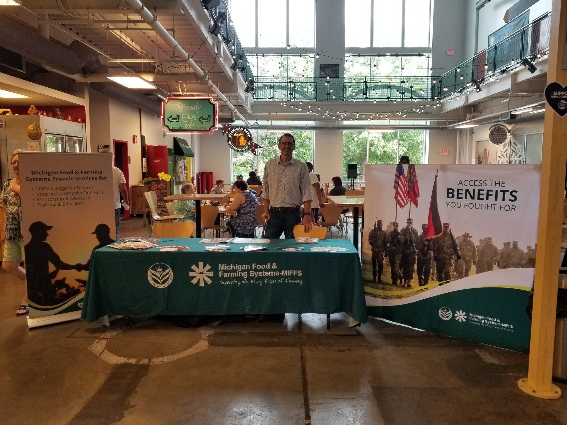 A man is standing in front of a table with a sign that says benefits.