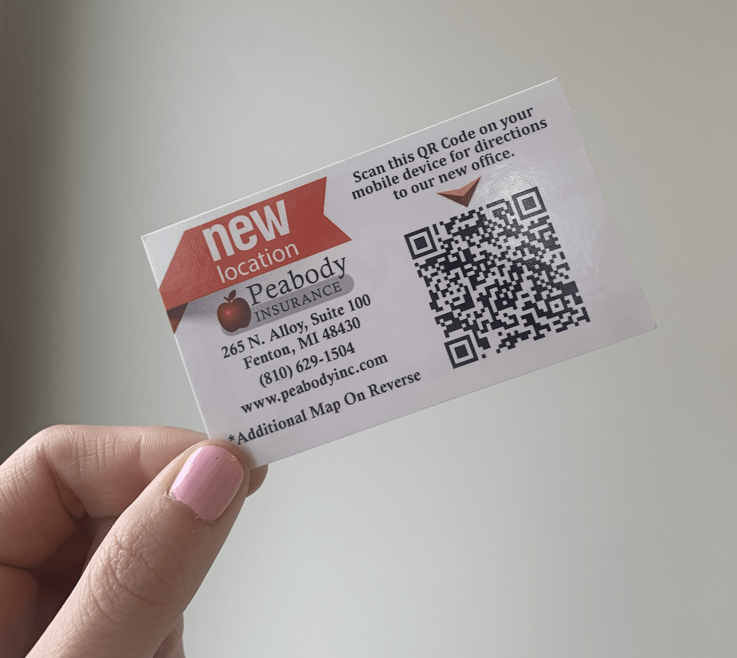 A person is holding a business card with a qr code on it.