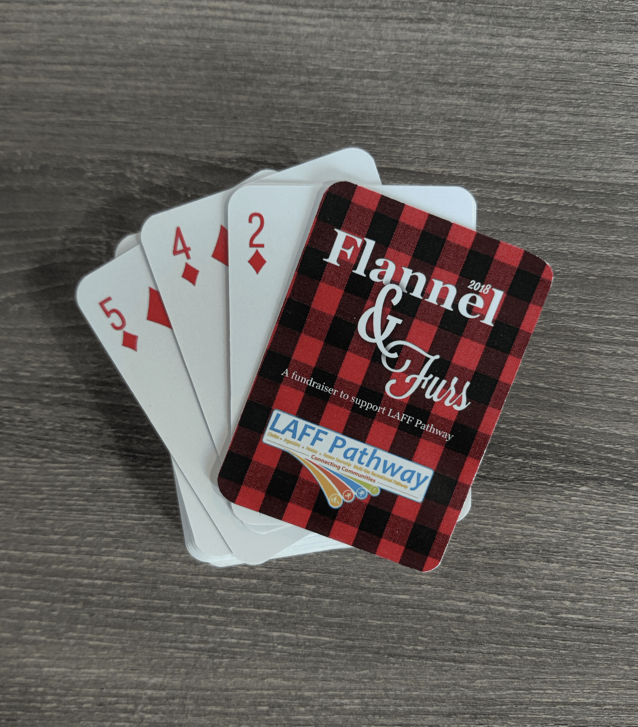 Four playing cards are stacked on top of each other on a wooden table.