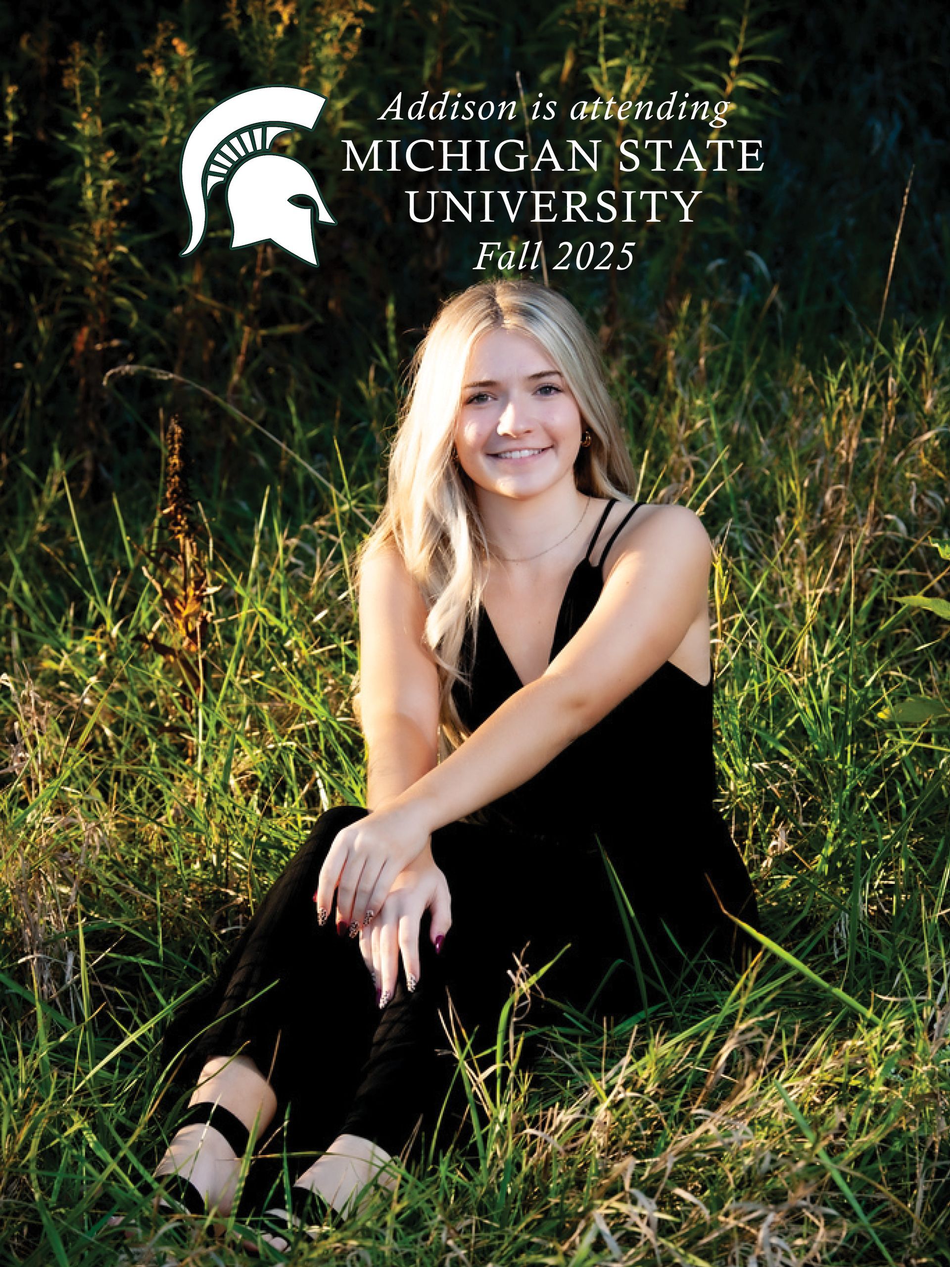 A woman in a black dress is sitting in the grass.
