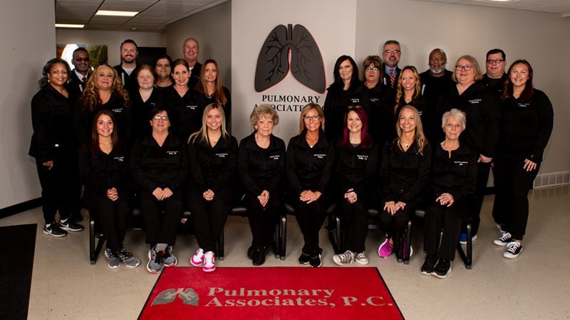 A group of people are posing for a picture in front of a sign that says pulmonary associates p.c.