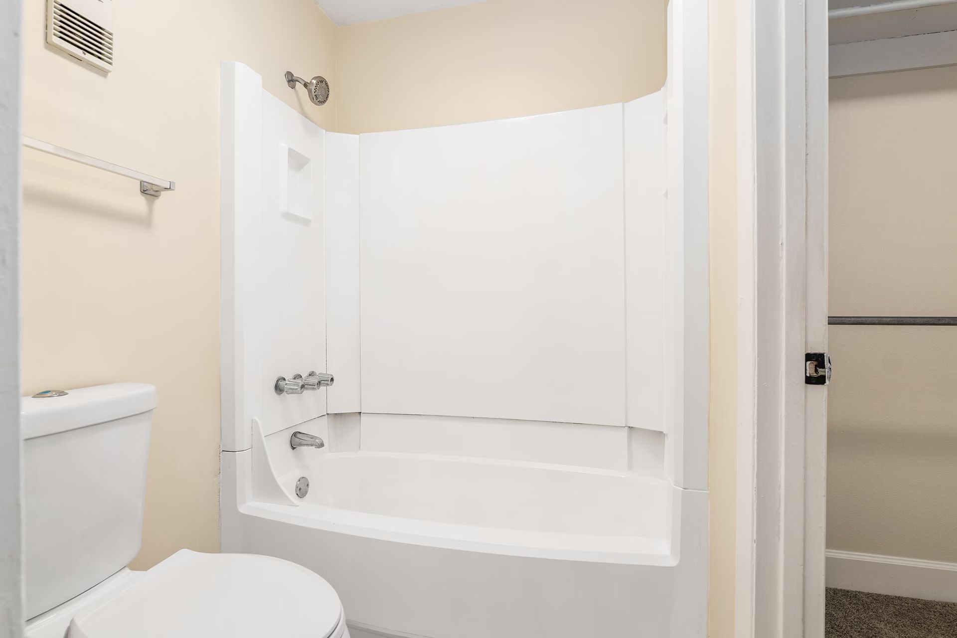 White bathroom with a toilet, shower/tub, and closet.