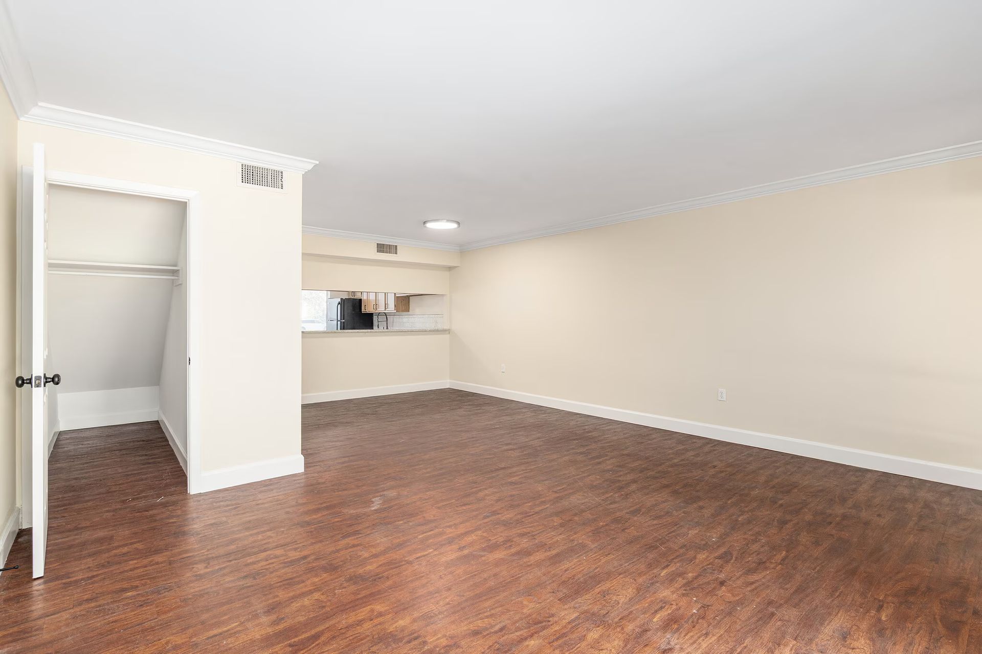 Empty apartment living room with hardwood floors, cream walls, and a closet.
