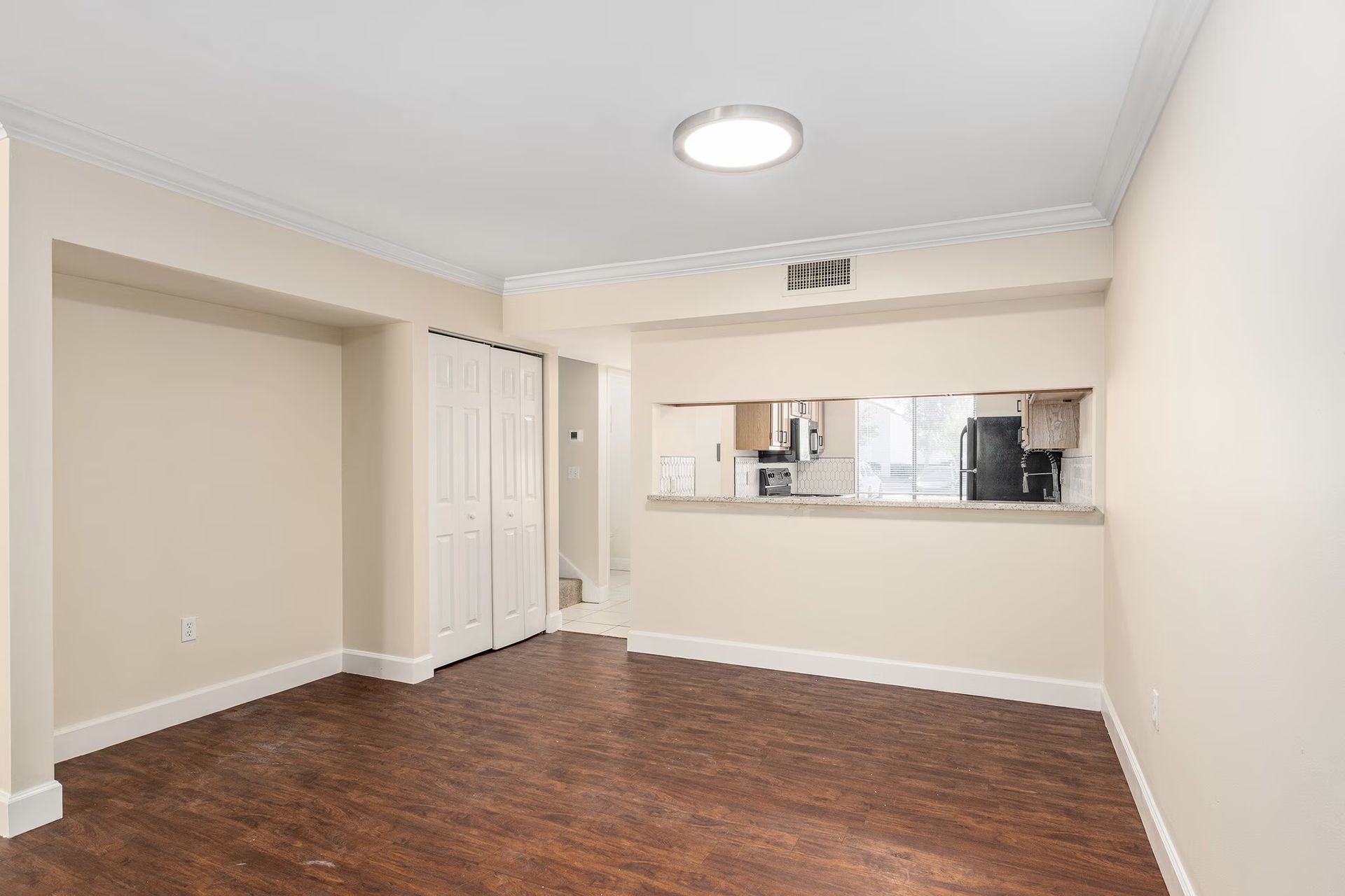 Empty dining room with wood floors and opening to kitchen.
