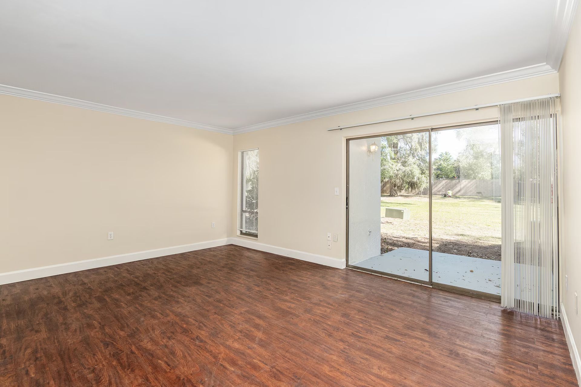 Empty room with wood floor, sliding glass door, and neutral walls.