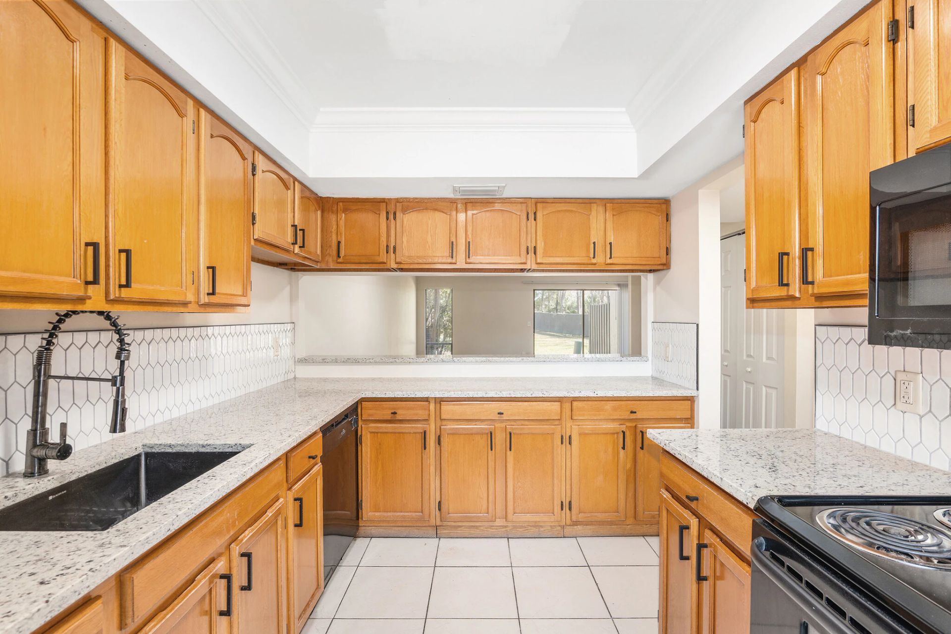 Kitchen with light brown cabinets, black appliances, and white countertops.