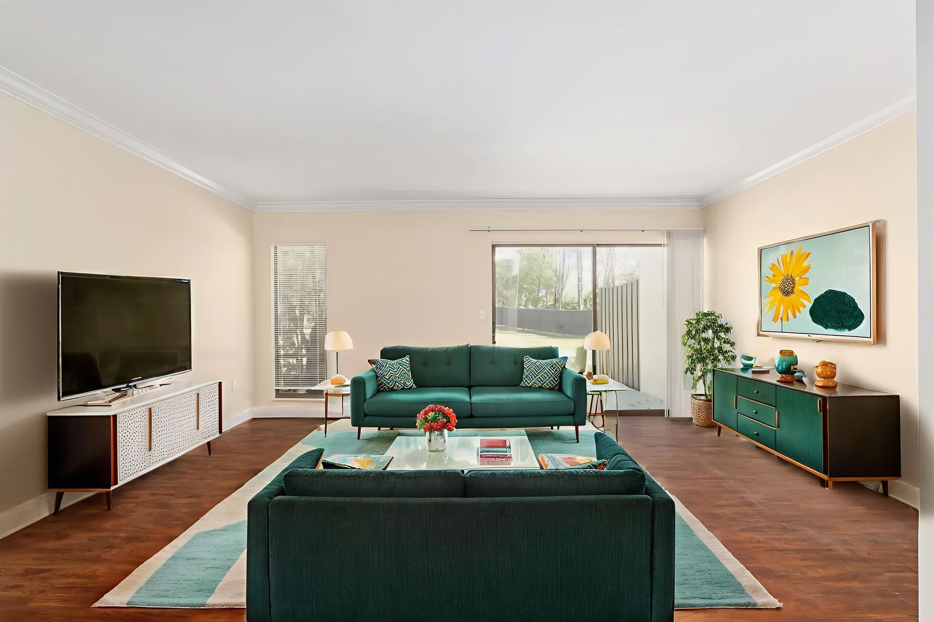 Living room with teal sofas, a floral rug, wooden floors, and a TV.