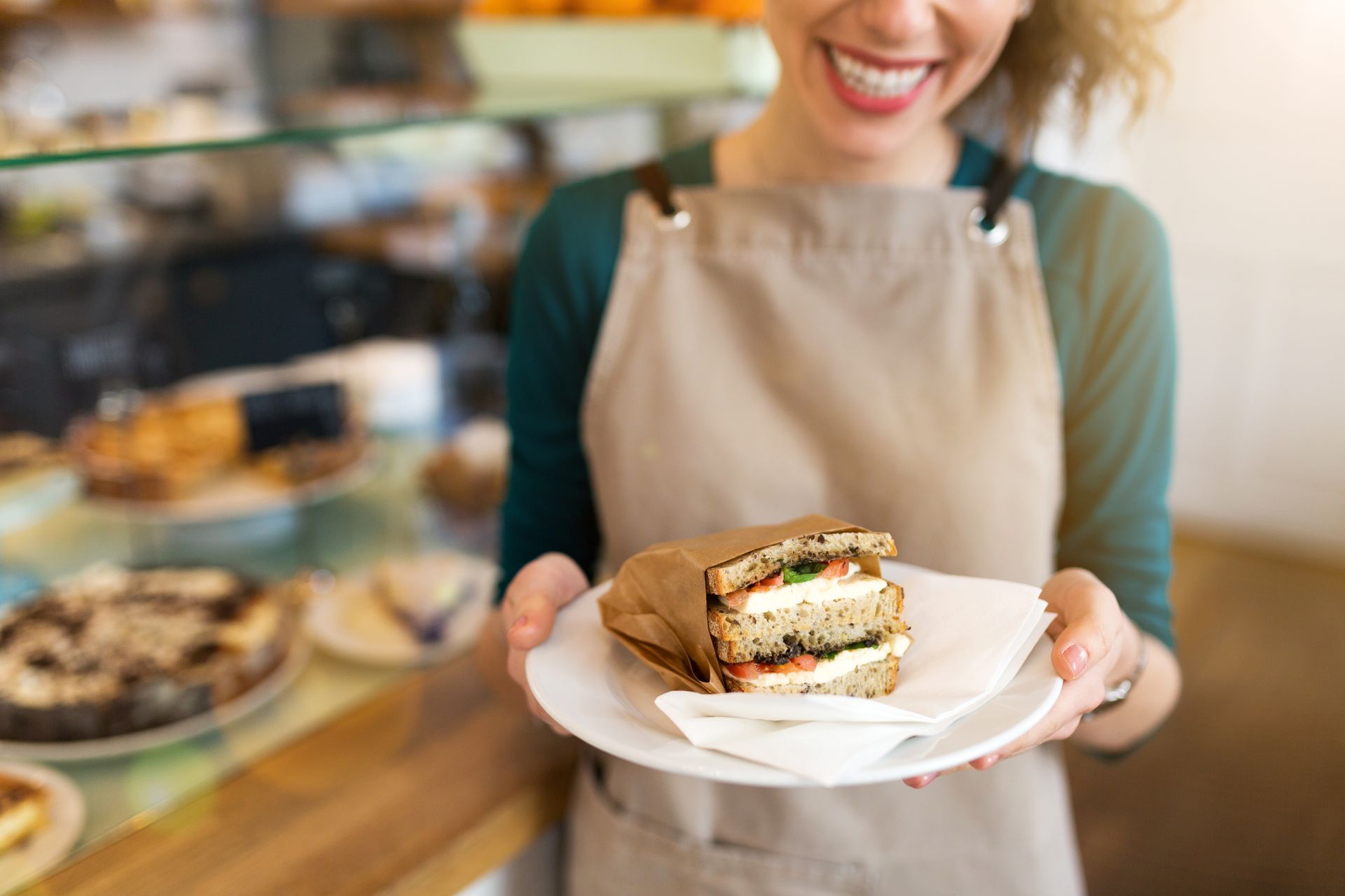 A woman is holding a plate of food in a bakery.
