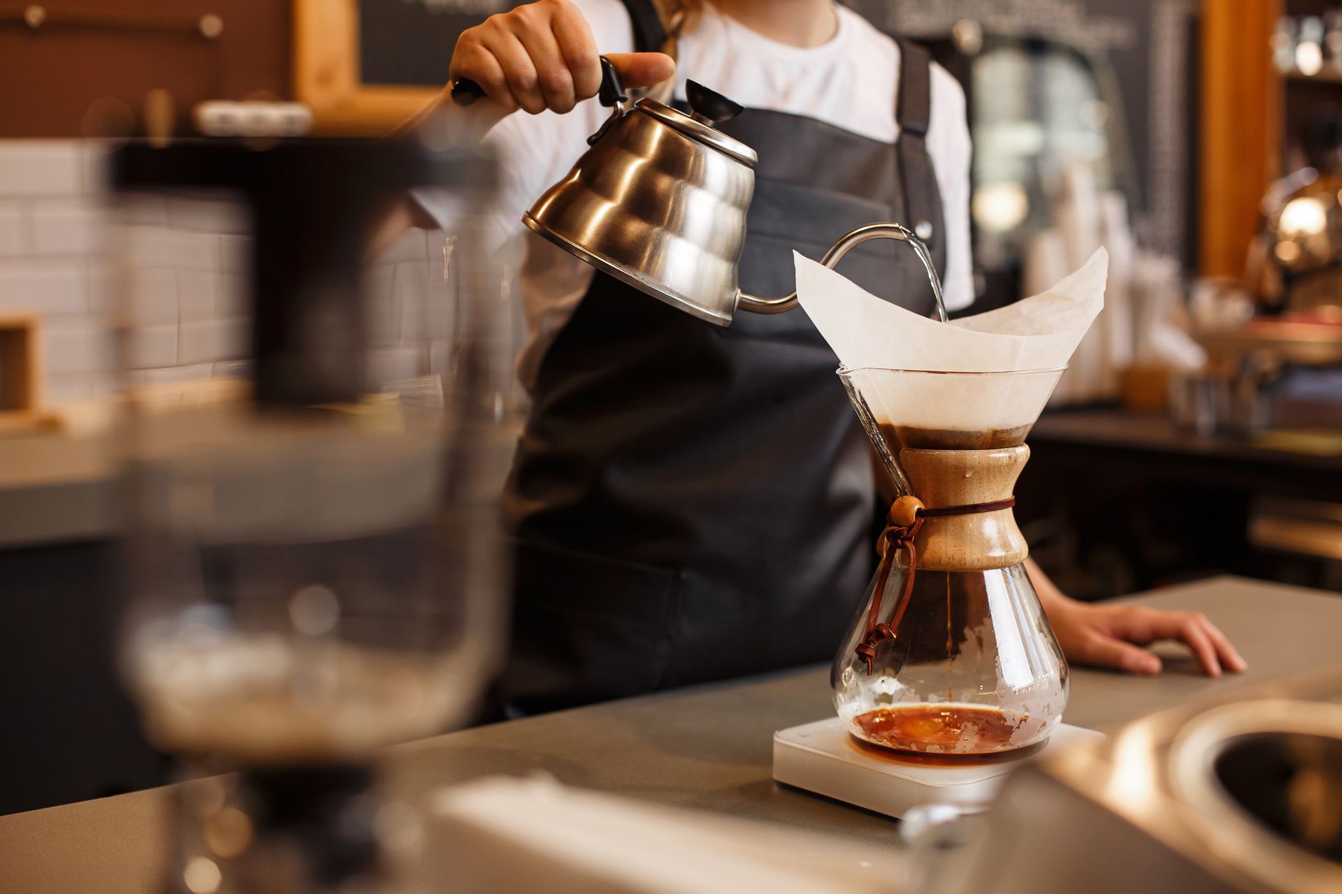 A barista is pouring coffee into a glass.