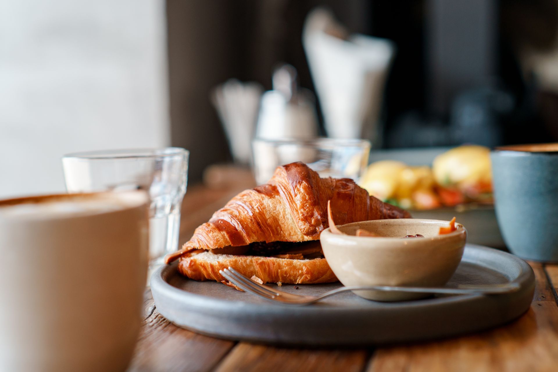 A close up of a croissant on a plate on a table.
