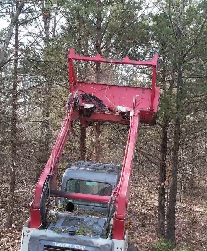Red and gray track loader in a field clearing debris.