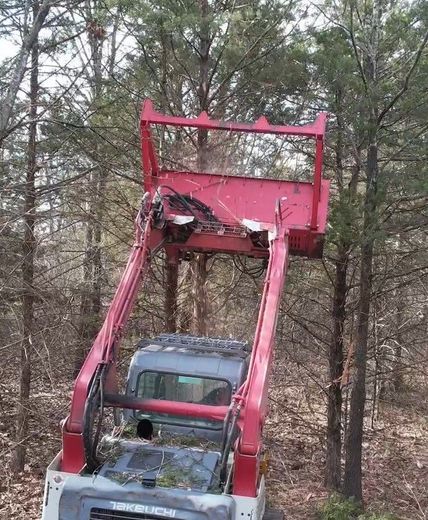 Red and gray track loader in a field clearing debris.