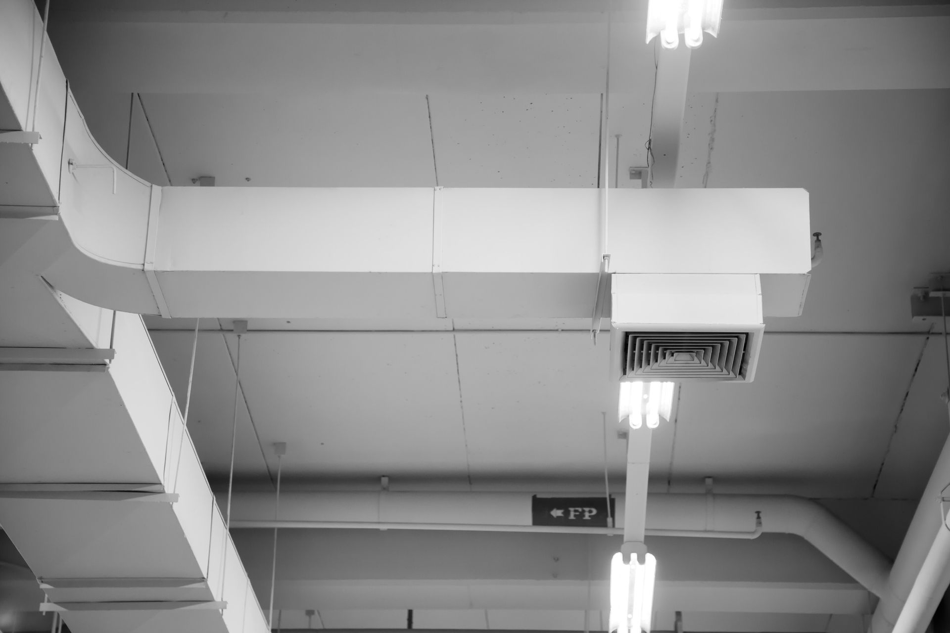 A black and white photo of a ceiling with a lot of pipes hanging from it.