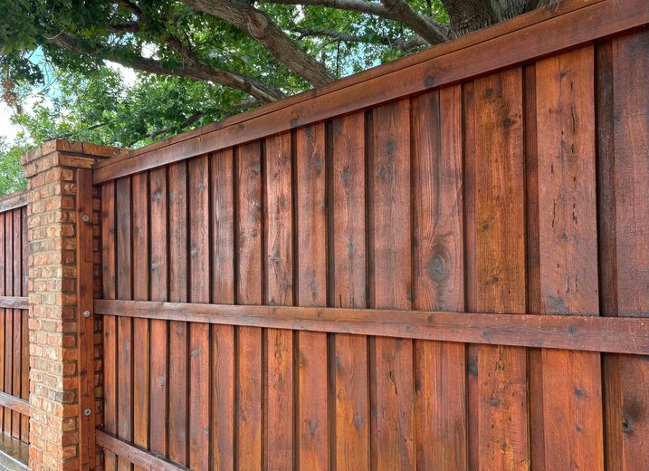 Wooden fence with brick pillar; stained reddish-brown.