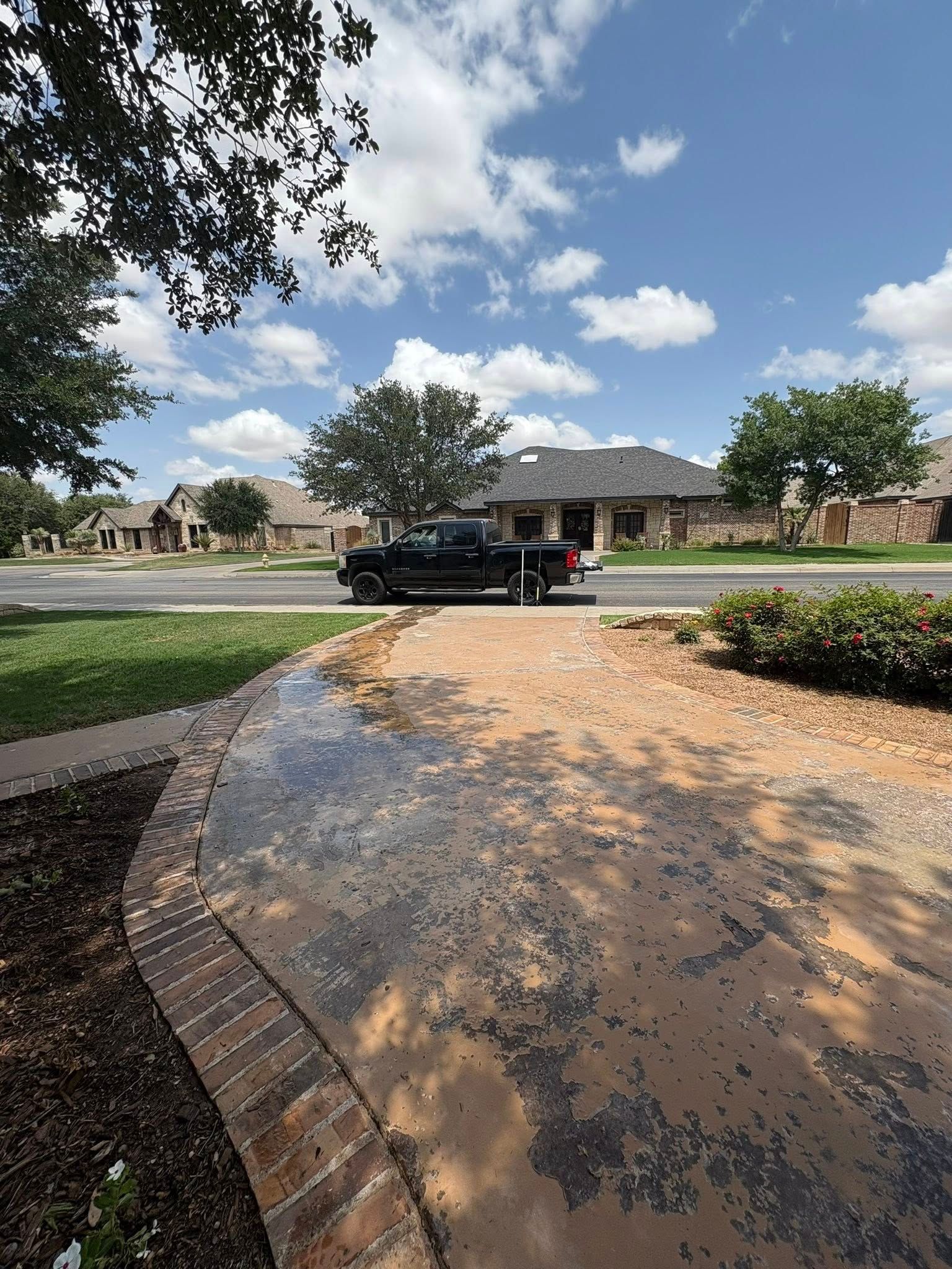 Black truck parked on street in front of house on a sunny day.